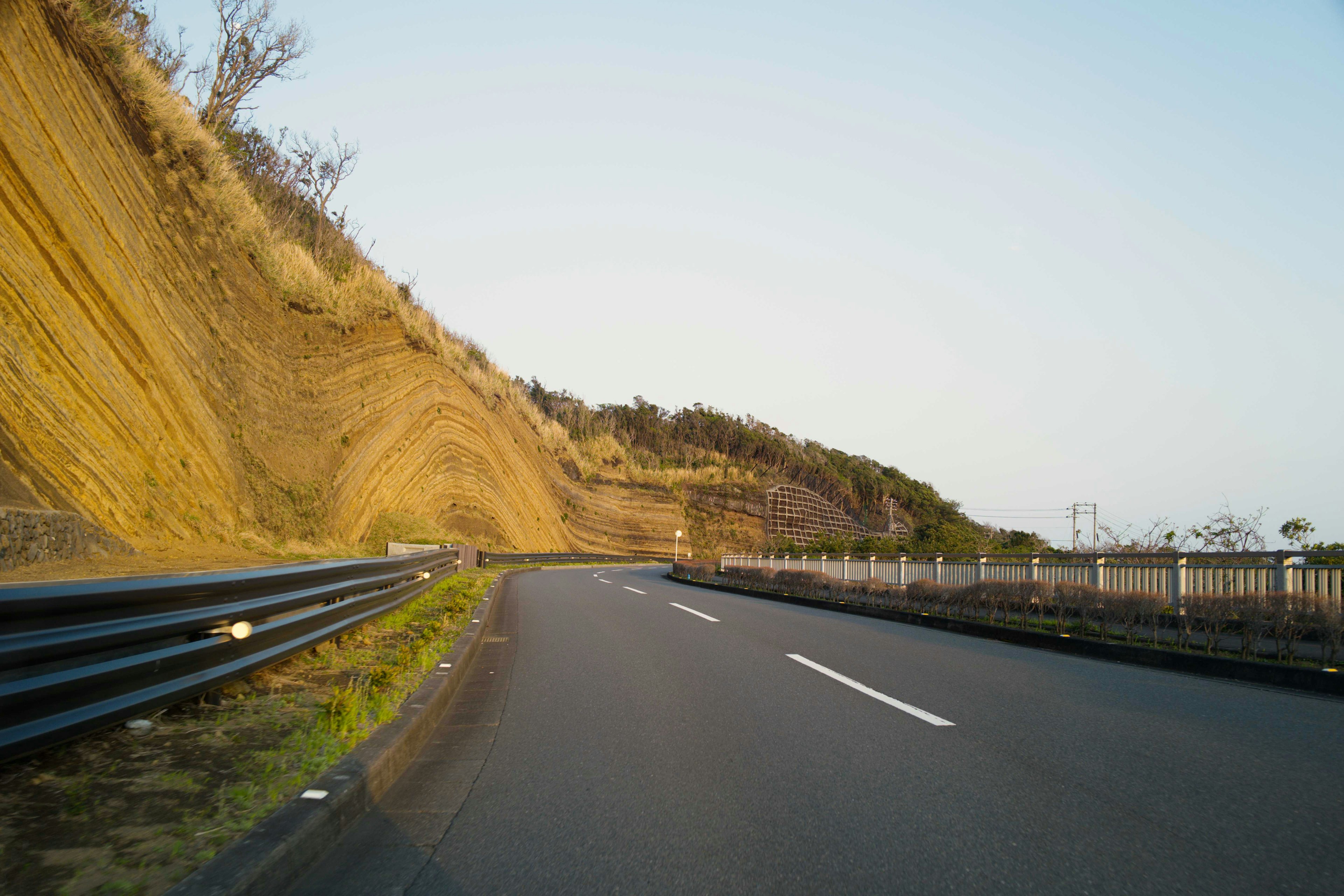 Curved road with a hillside and clear blue sky