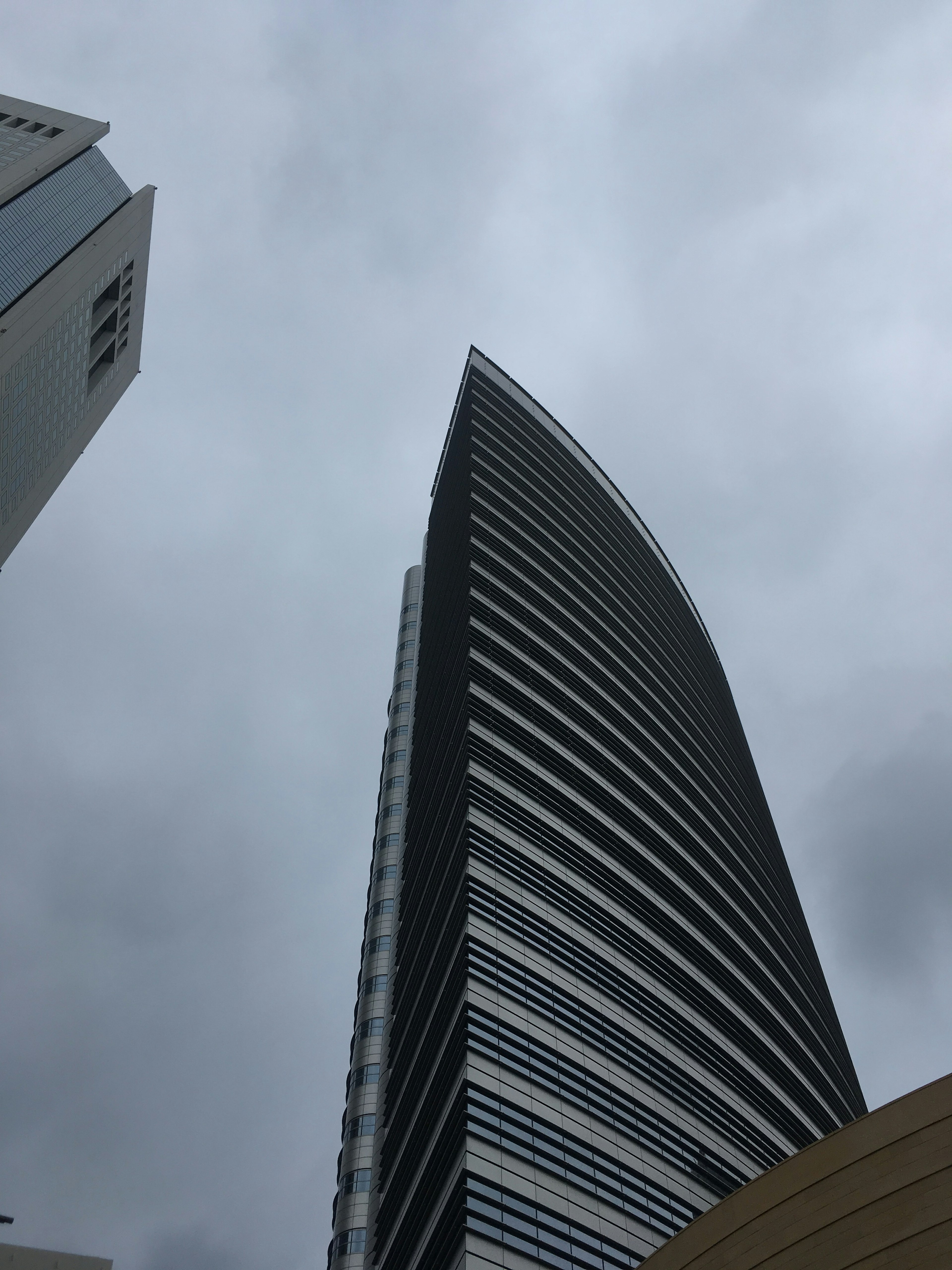 Blick auf einen modernen Wolkenkratzer von unten mit bewölktem Himmel im Hintergrund