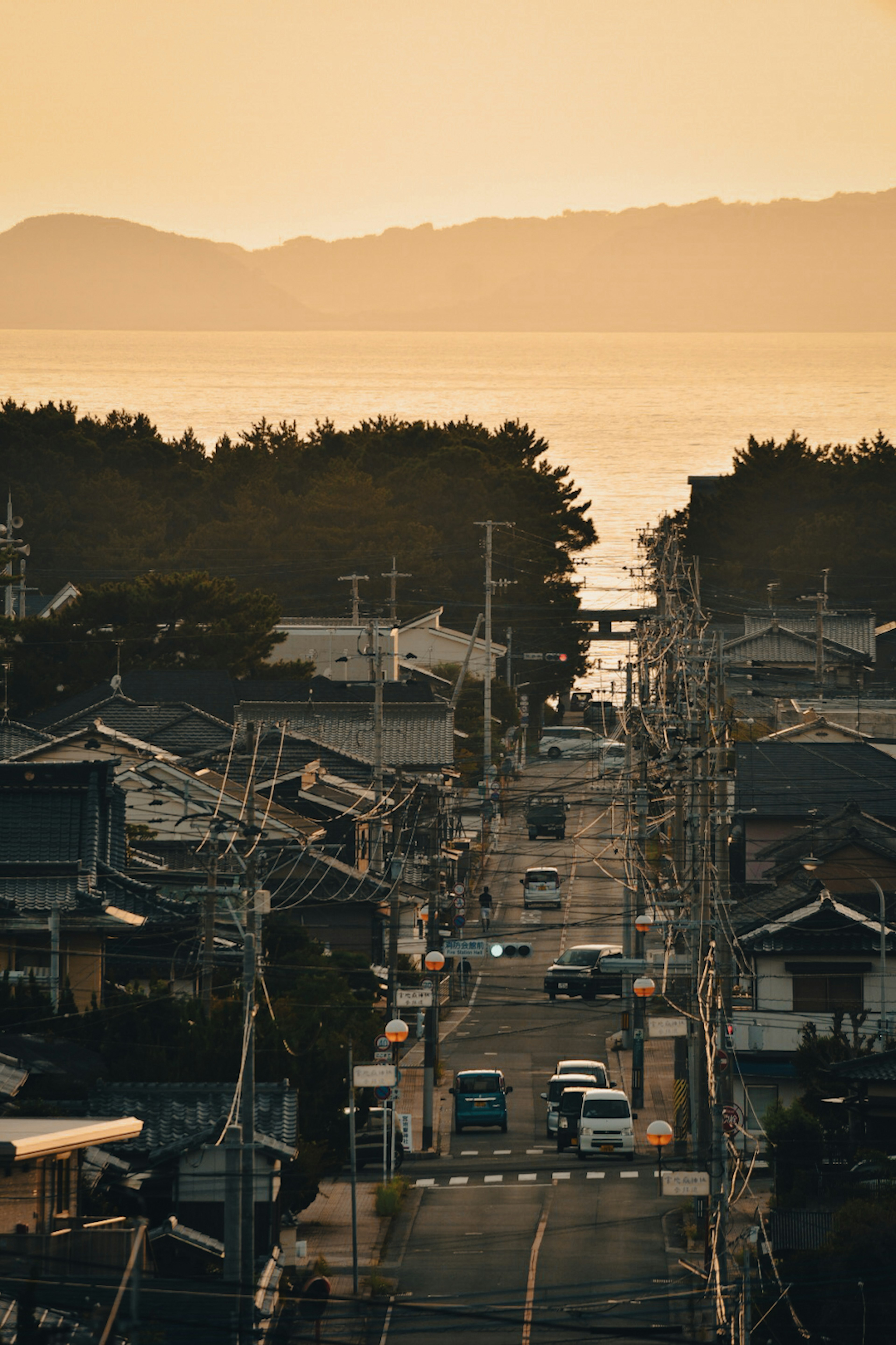 夕暮れの海辺の町並み 道路に沿った家々と車両 ほのかなオレンジ色の空