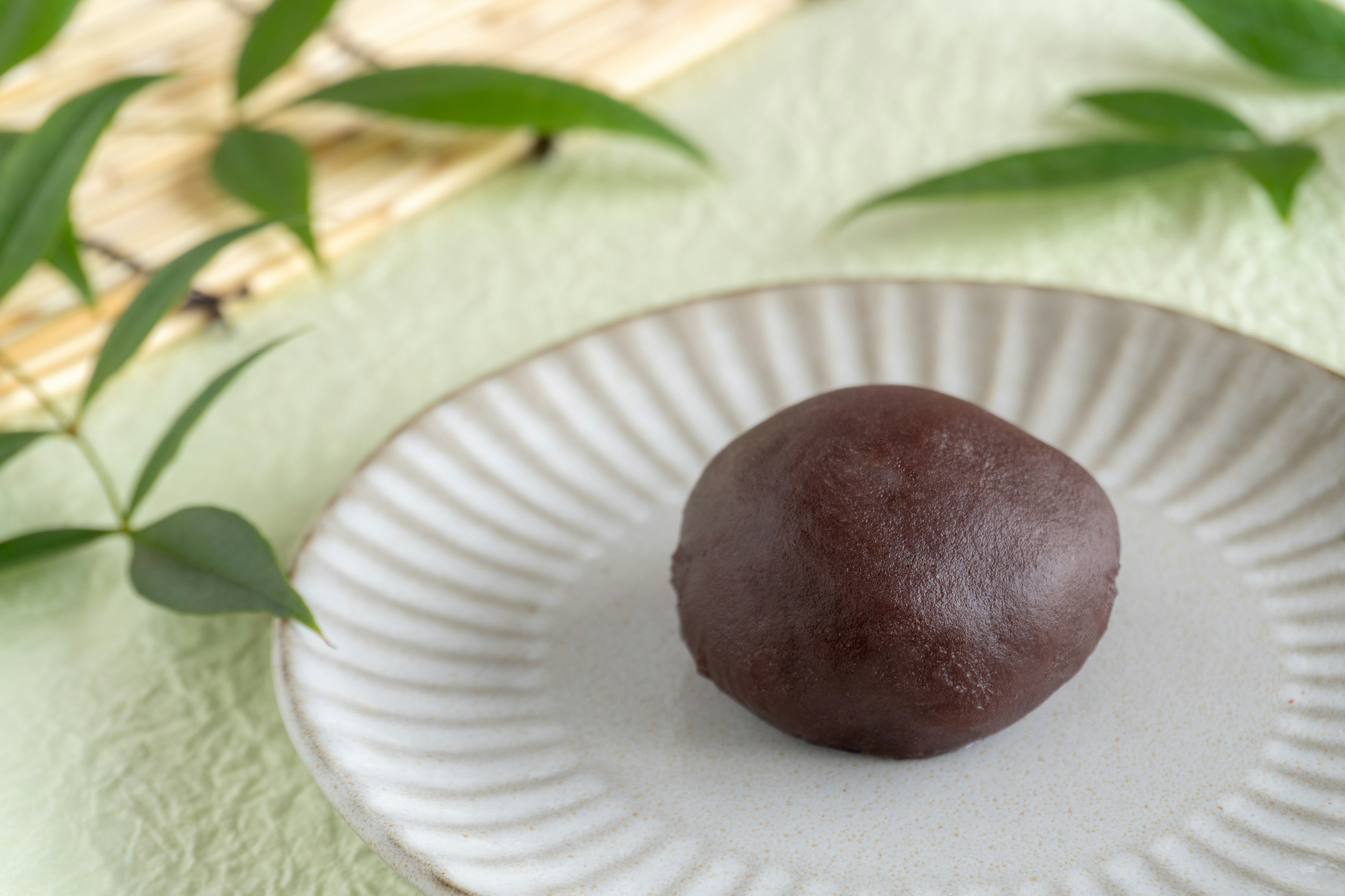 Un dulce japonés negro brillante en un plato blanco sobre un fondo verde