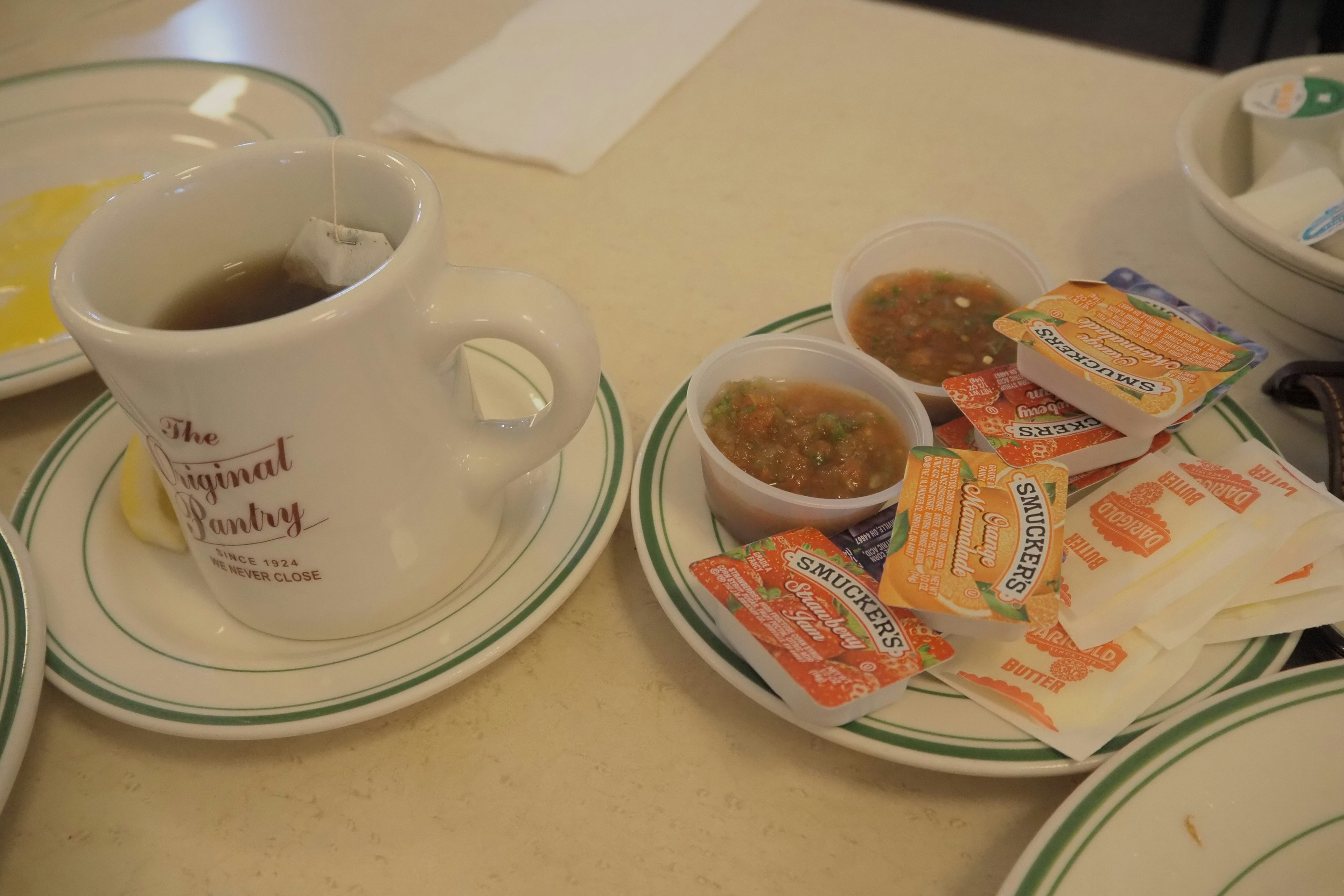 Coffee cup next to small plates of condiments and creamers