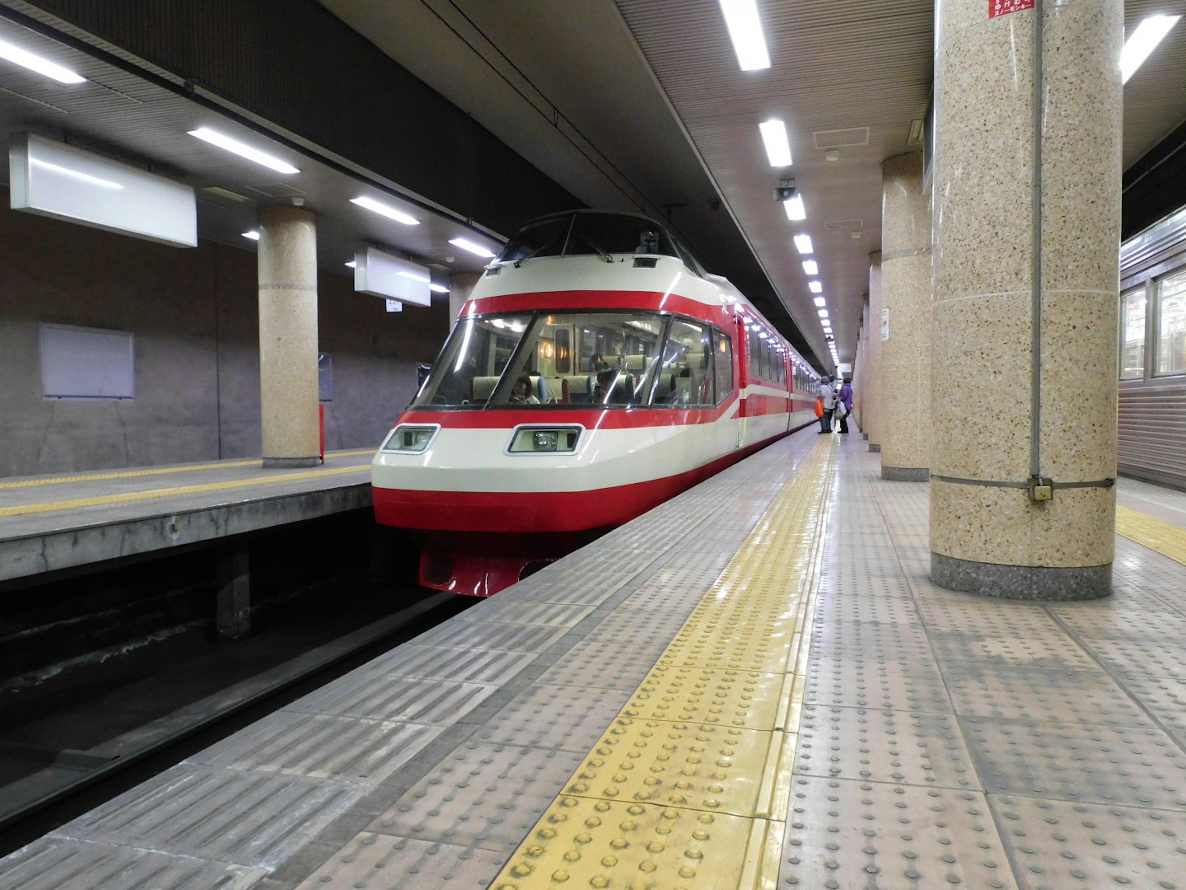 赤と白の電車が駅のプラットフォームに停車している様子