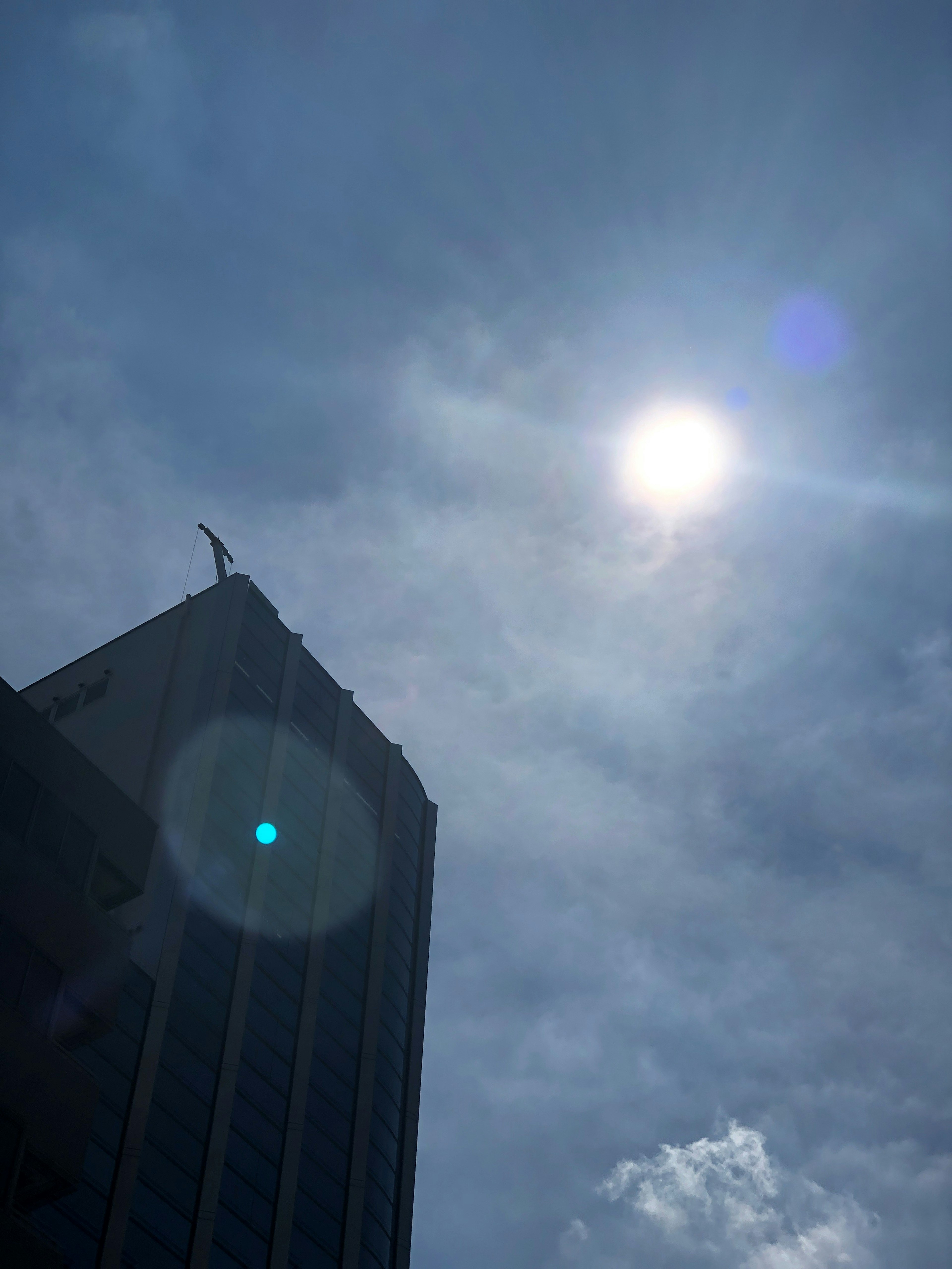 高いビルの上にある彫像と明るい太陽を背景にした雲のある空