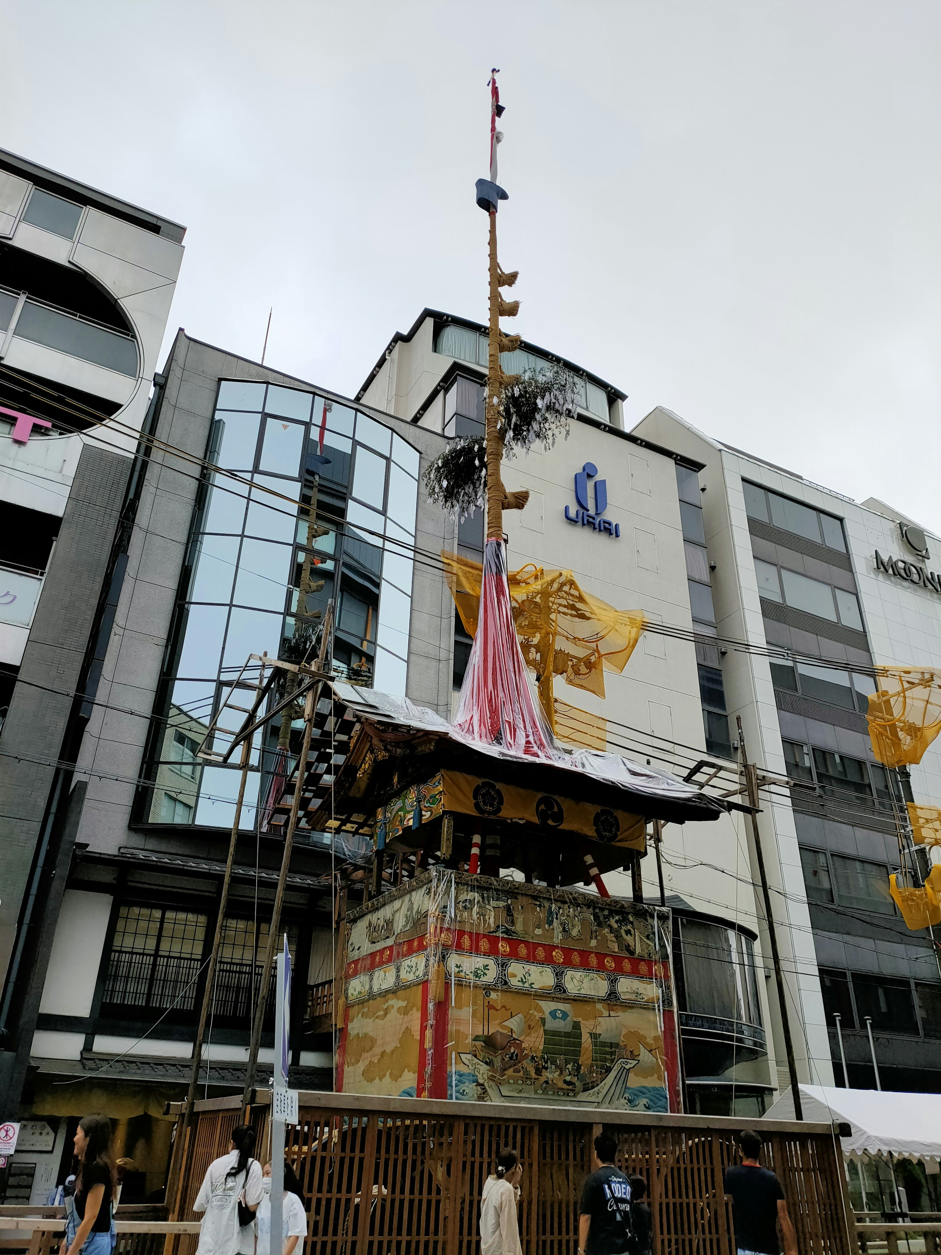 Un char traditionnel de festival se dresse devant des bâtiments modernes