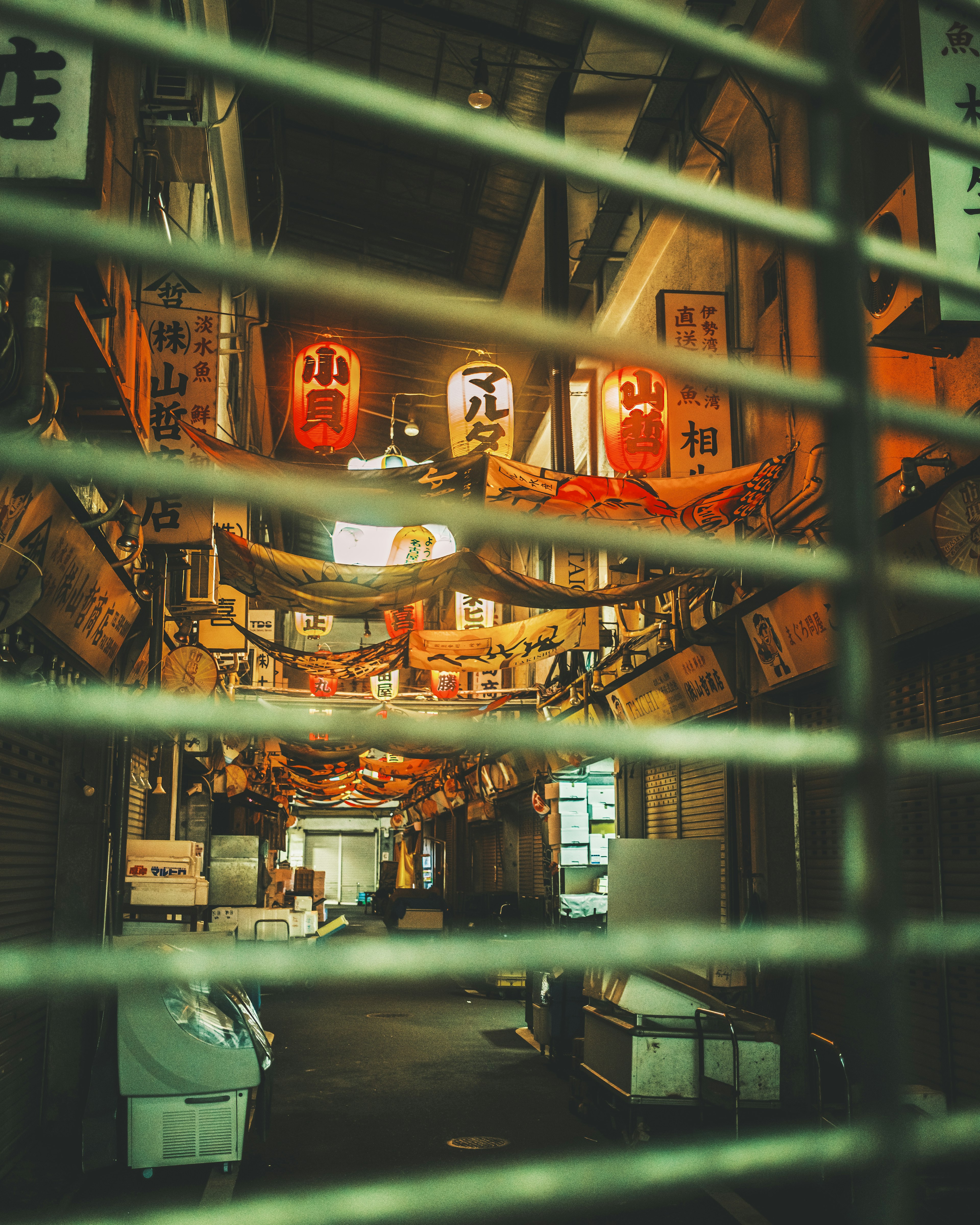 View of a lively market street adorned with lanterns and signs through a shutter