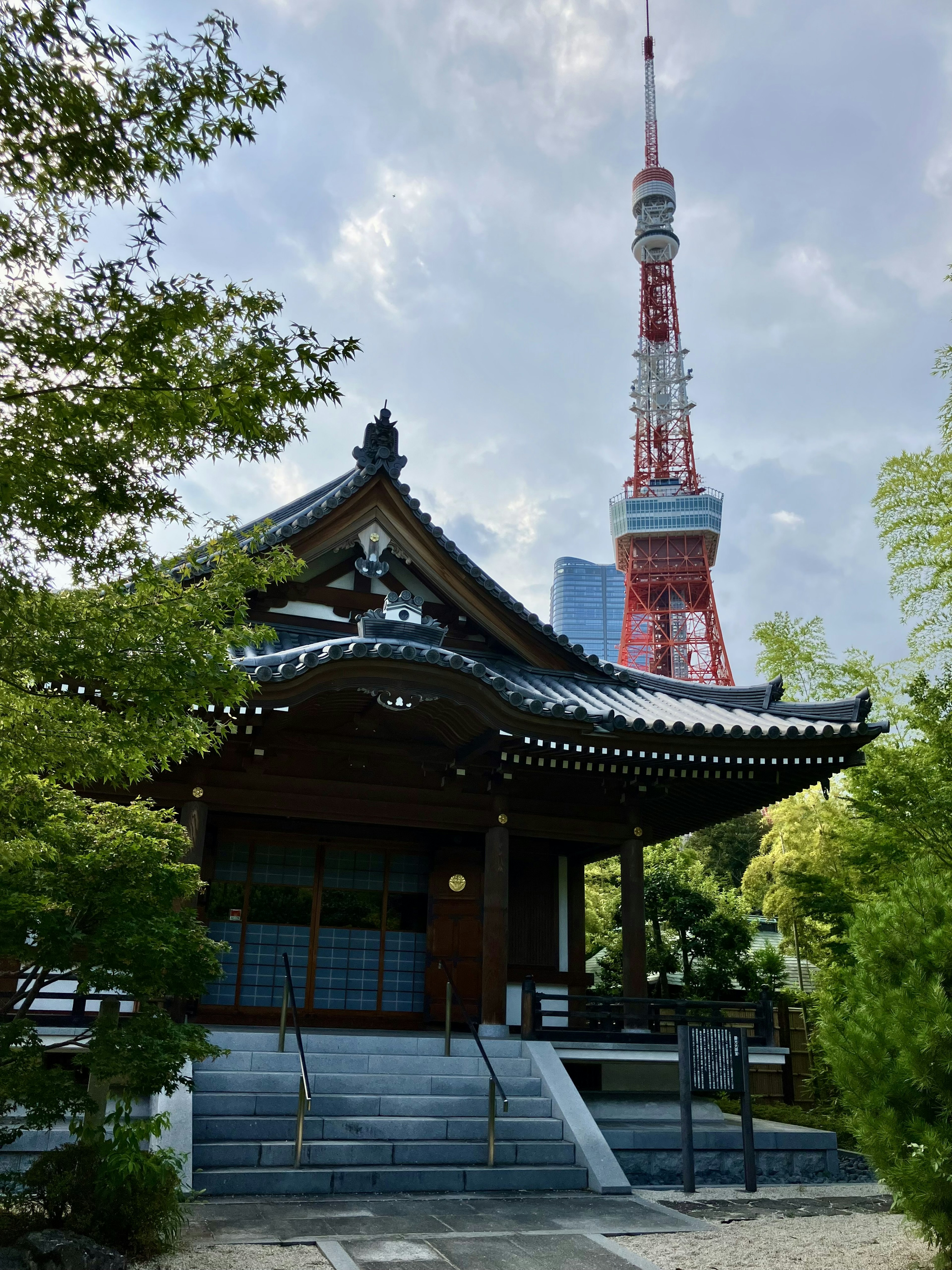 Contrasto tra la Torre di Tokyo e un tempio tradizionale circondato da vegetazione