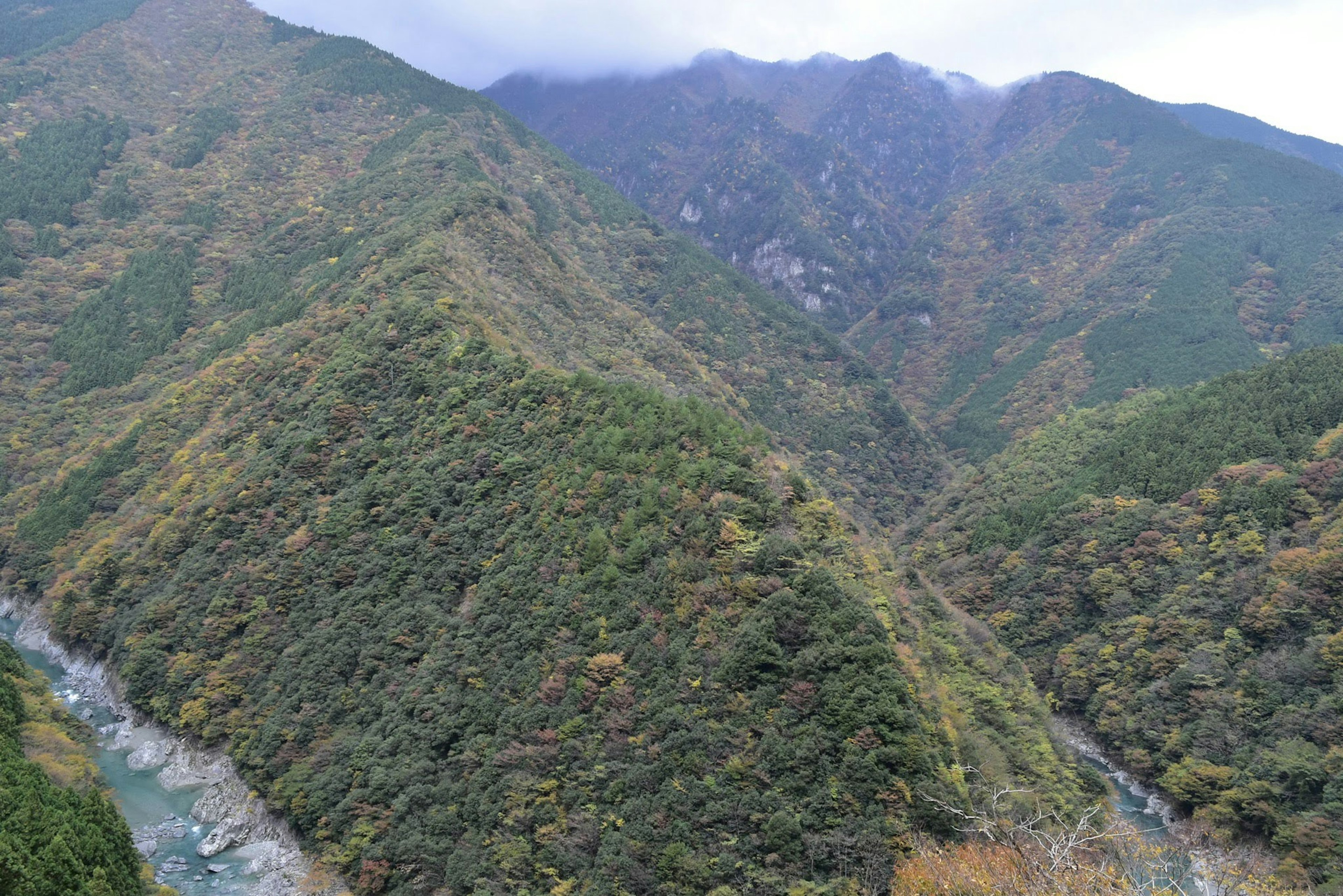 Gunung hijau subur dengan sungai mengalir di lembah