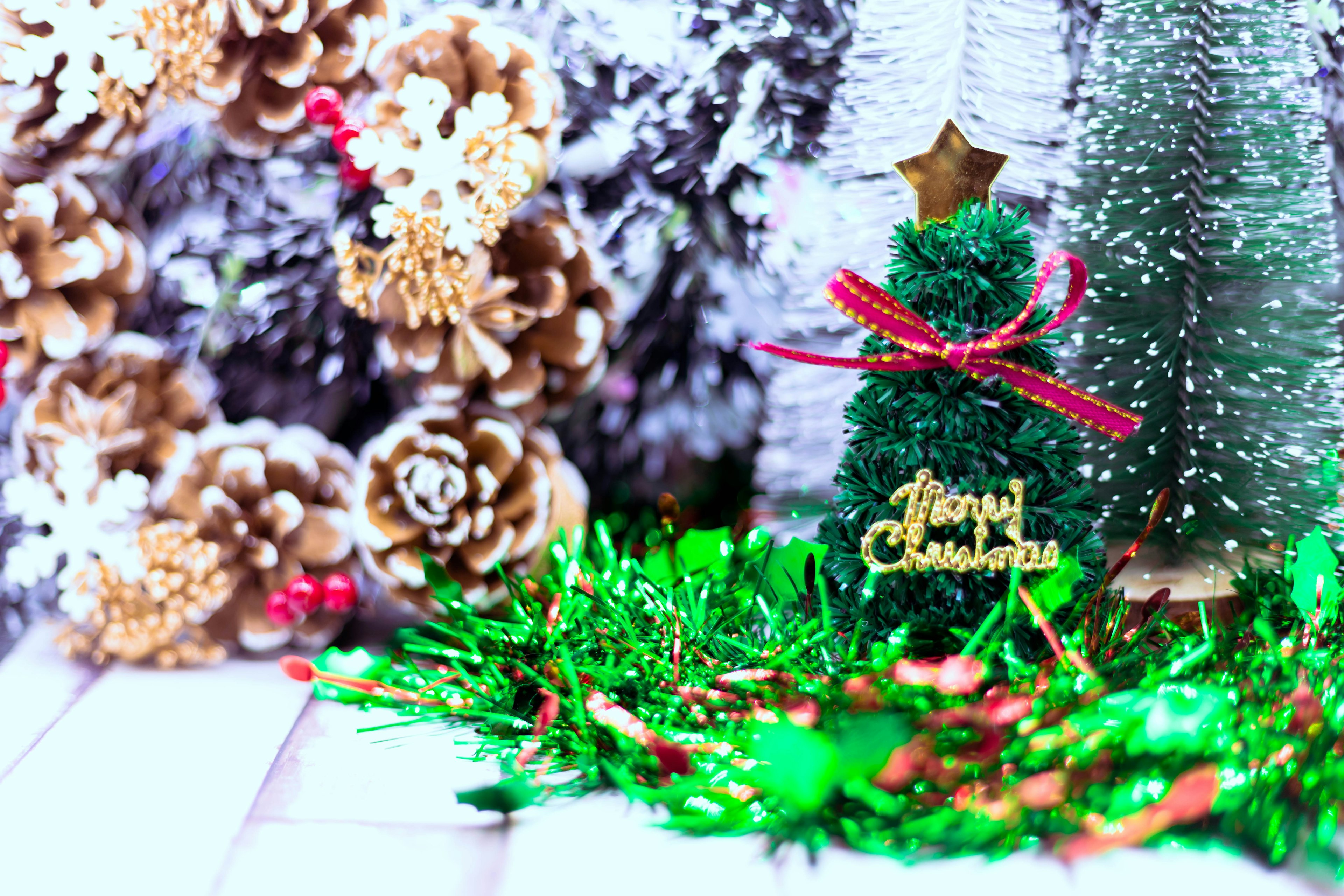 A small green Christmas tree with a star and ribbon surrounded by festive decorations