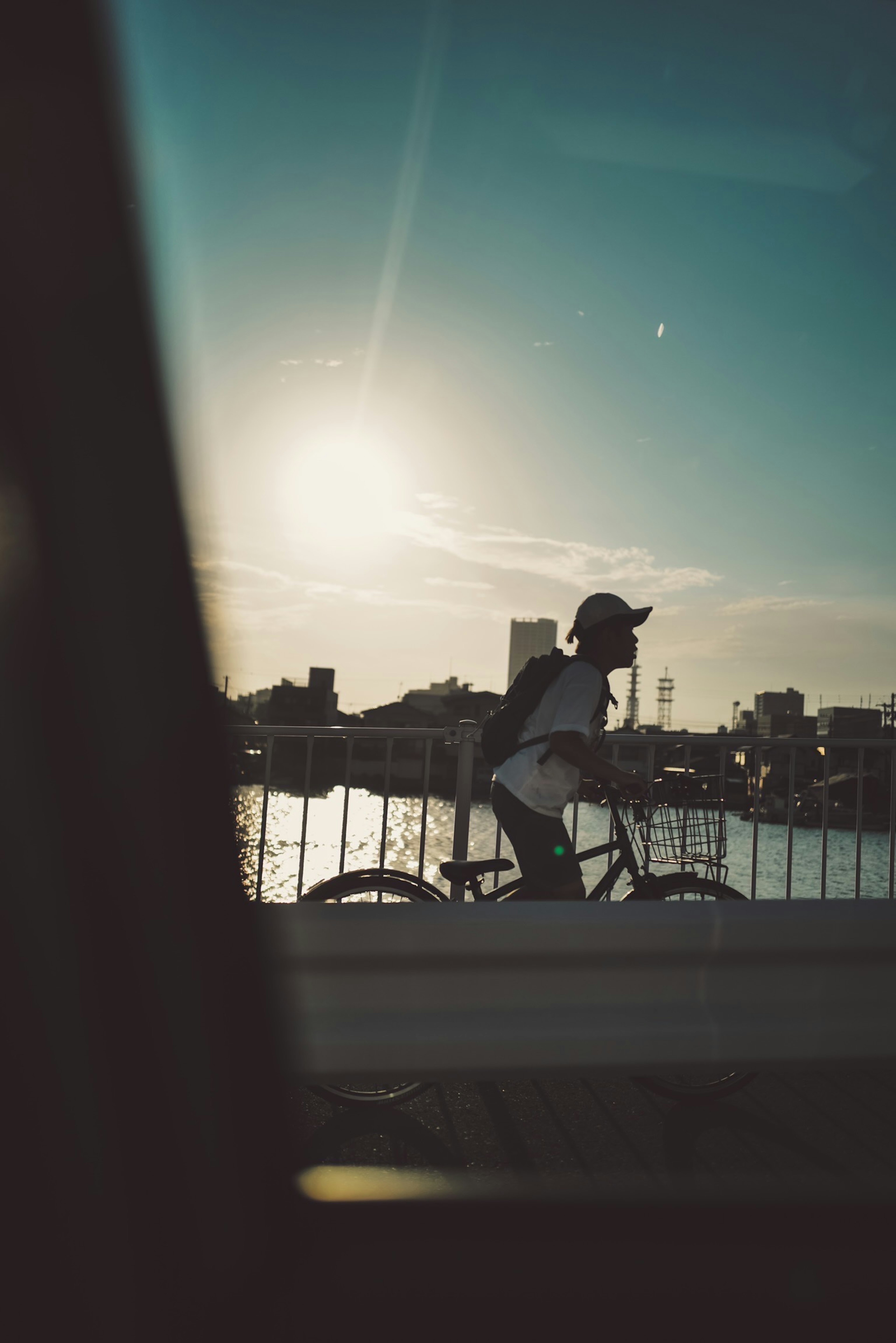 A person riding a bicycle across a bridge with the sunset in the background