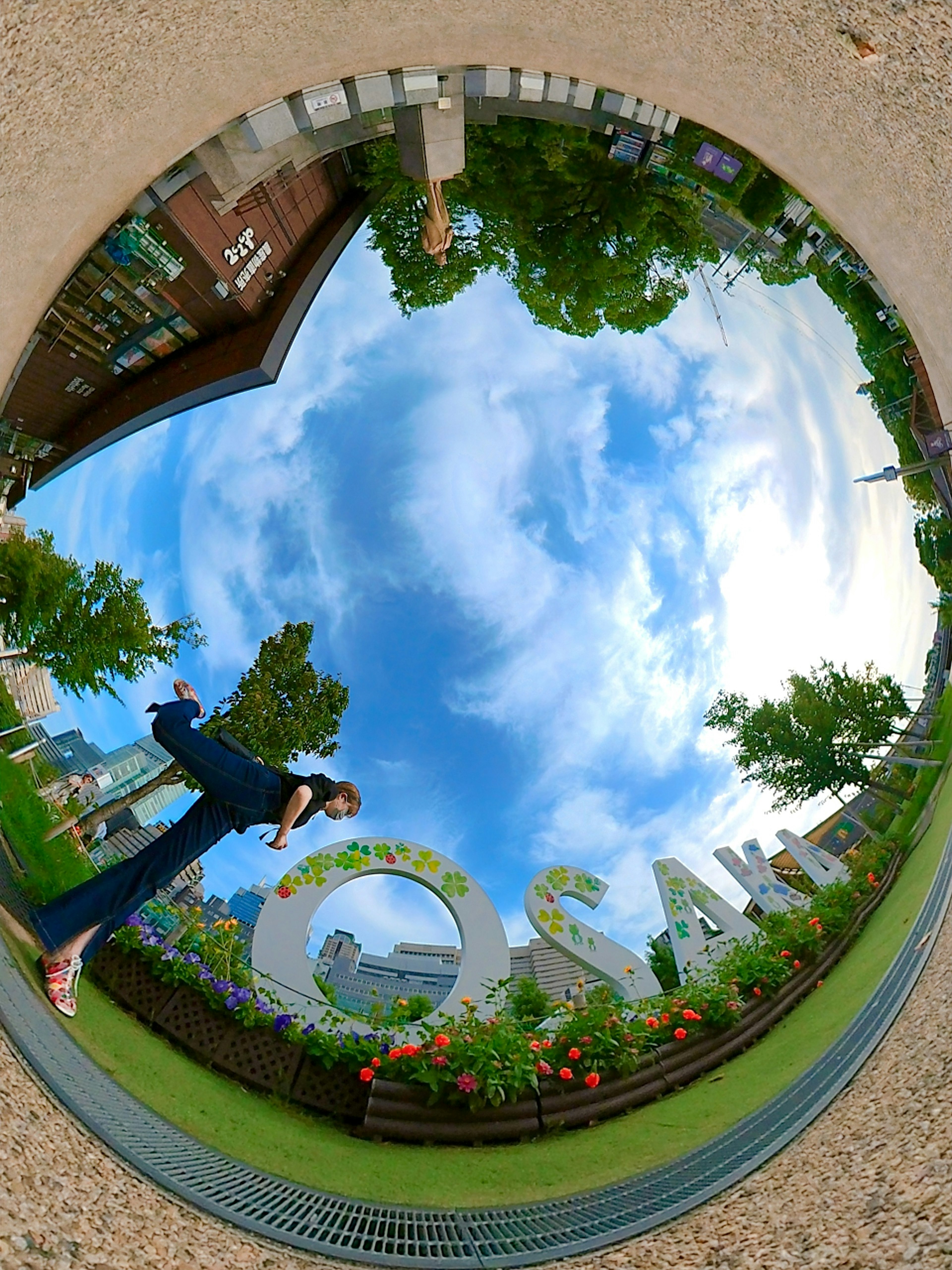 A round mirror reflecting a park scene with a person standing in front