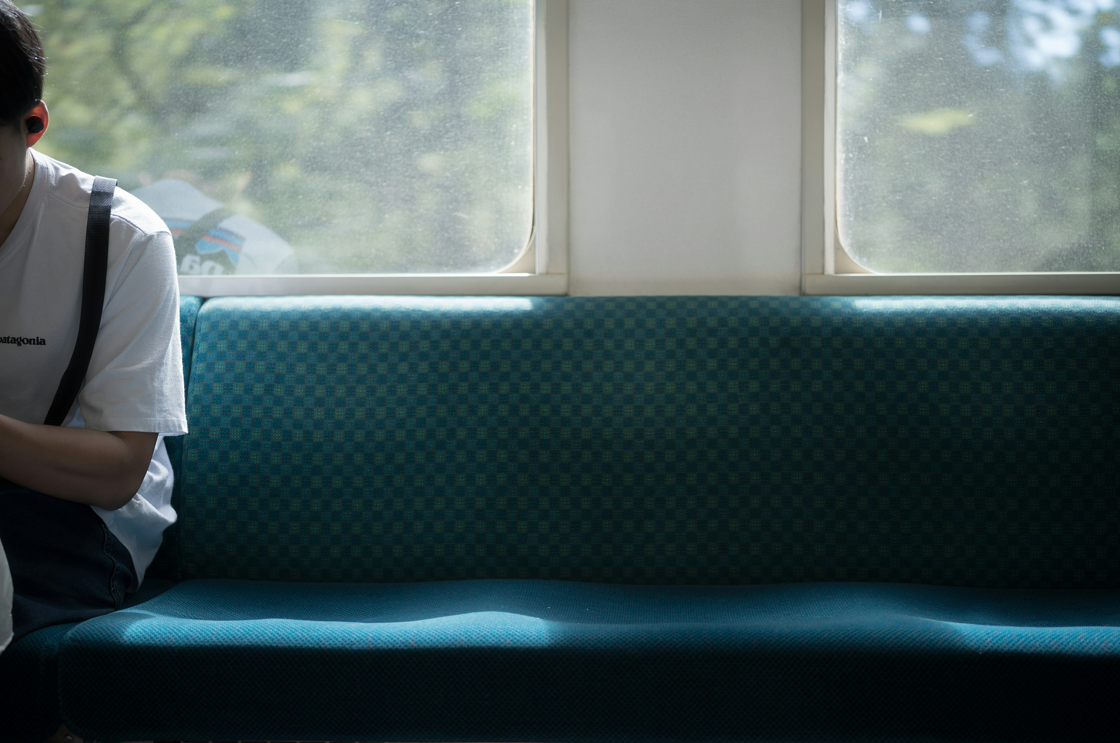 Mann sitzt auf einem blauen Sofa mit Sonnenlicht, das durch das Fenster fällt