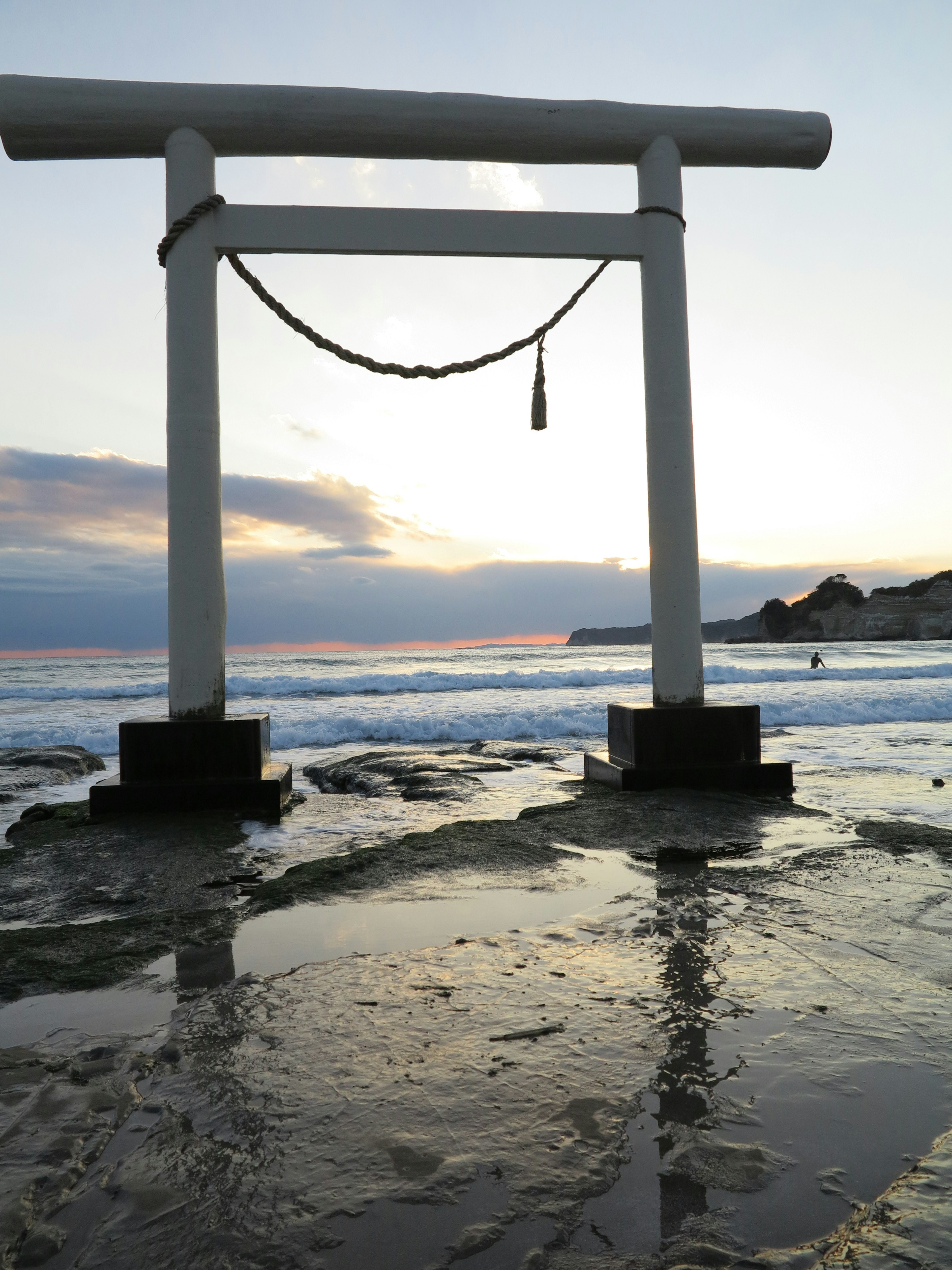 Silhouette torii di pantai saat matahari terbenam