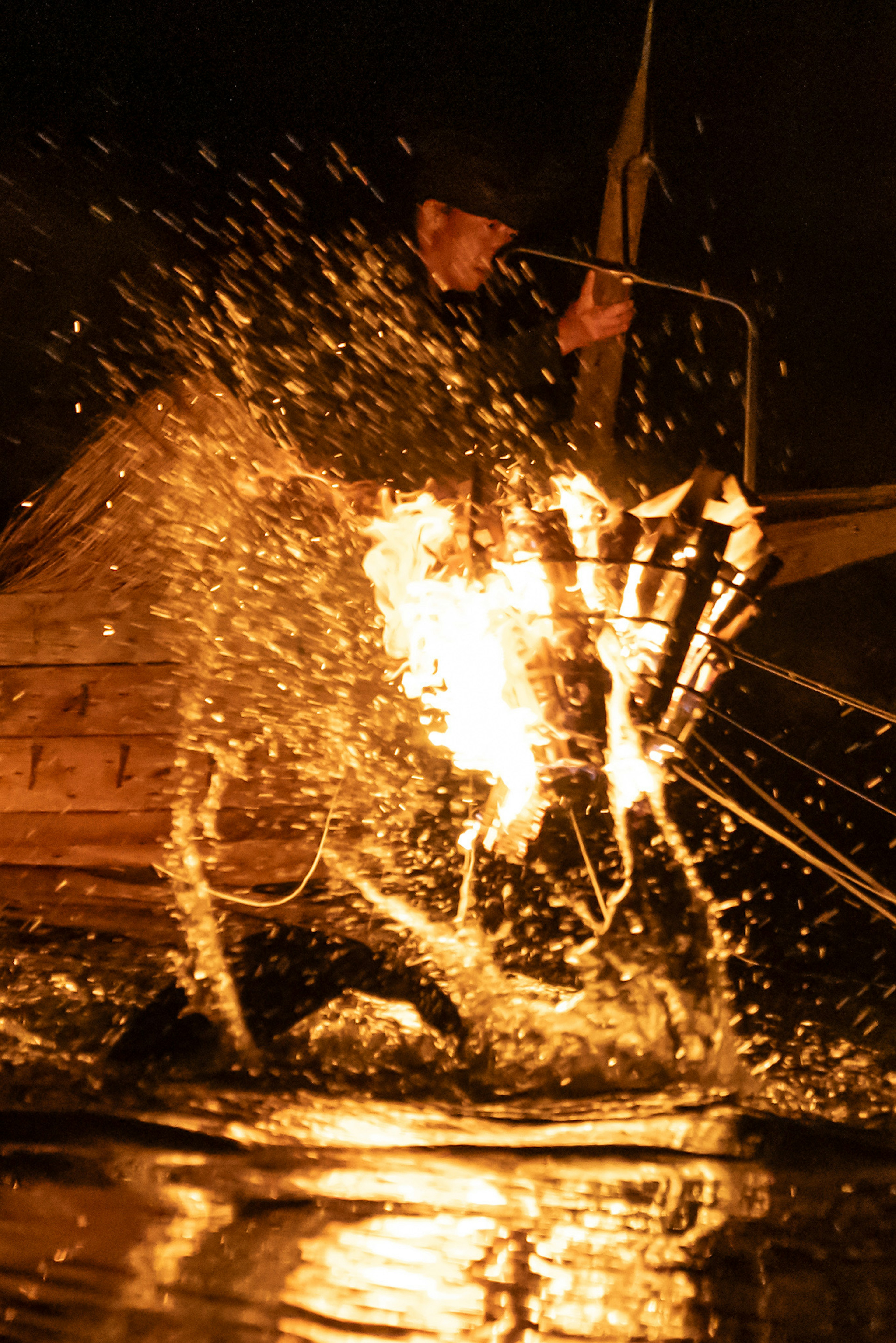 Silhouette of a fisherman creating sparks on the water surface