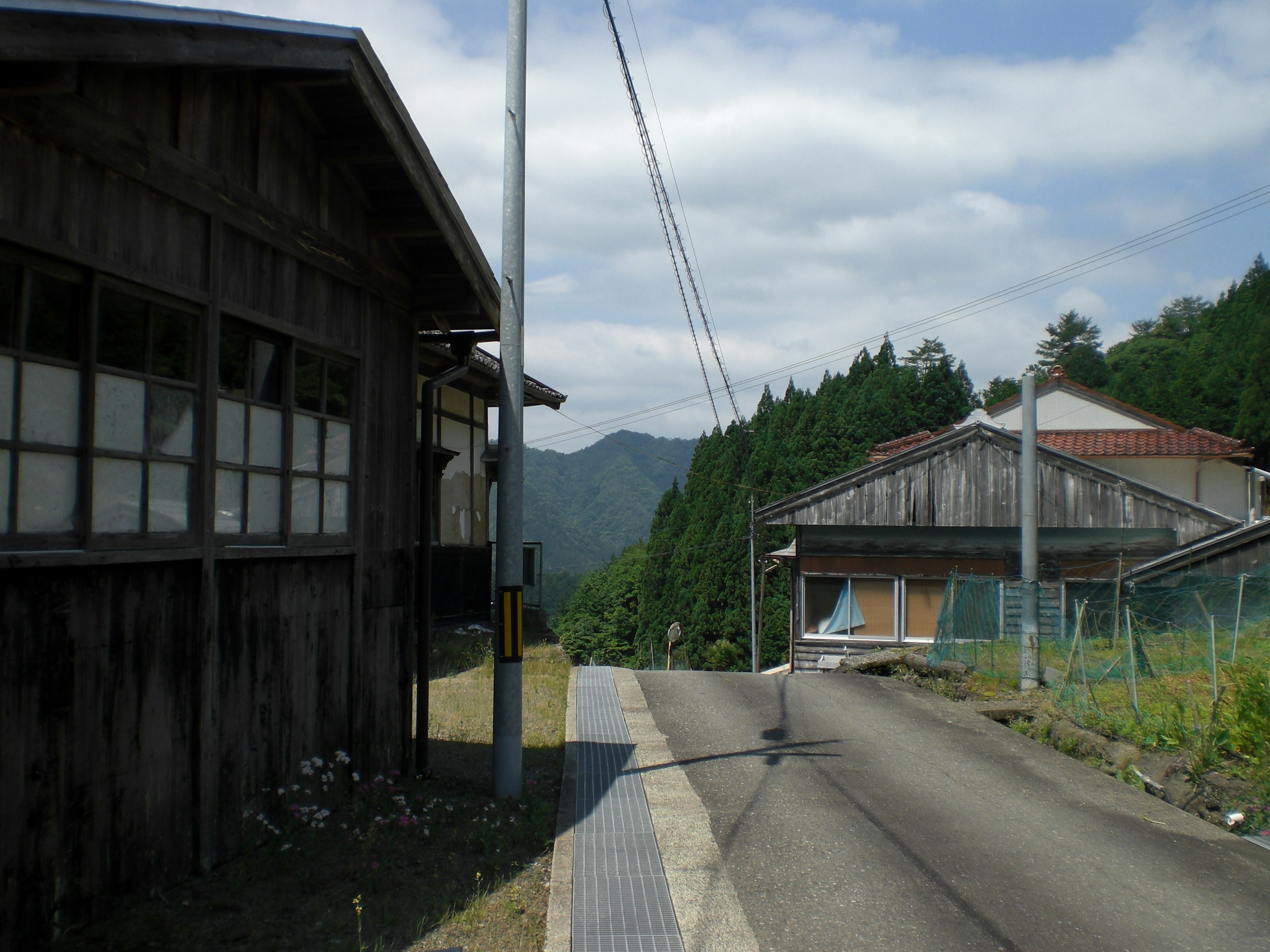 Paysage de village calme entouré de montagnes avec des bâtiments en bois anciens et une route pavée