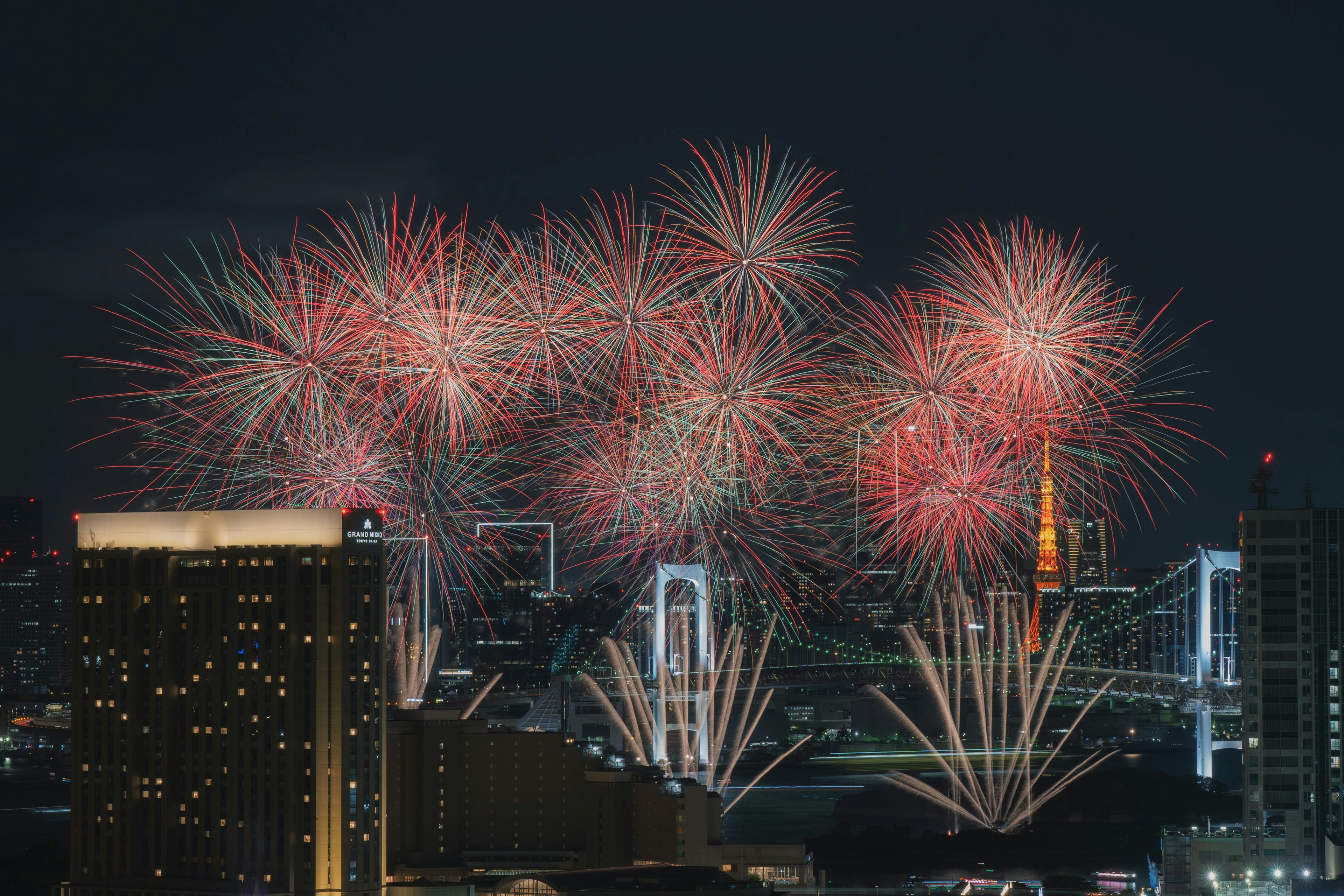 Espectáculo de fuegos artificiales iluminando el cielo nocturno de Tokio con el paisaje urbano