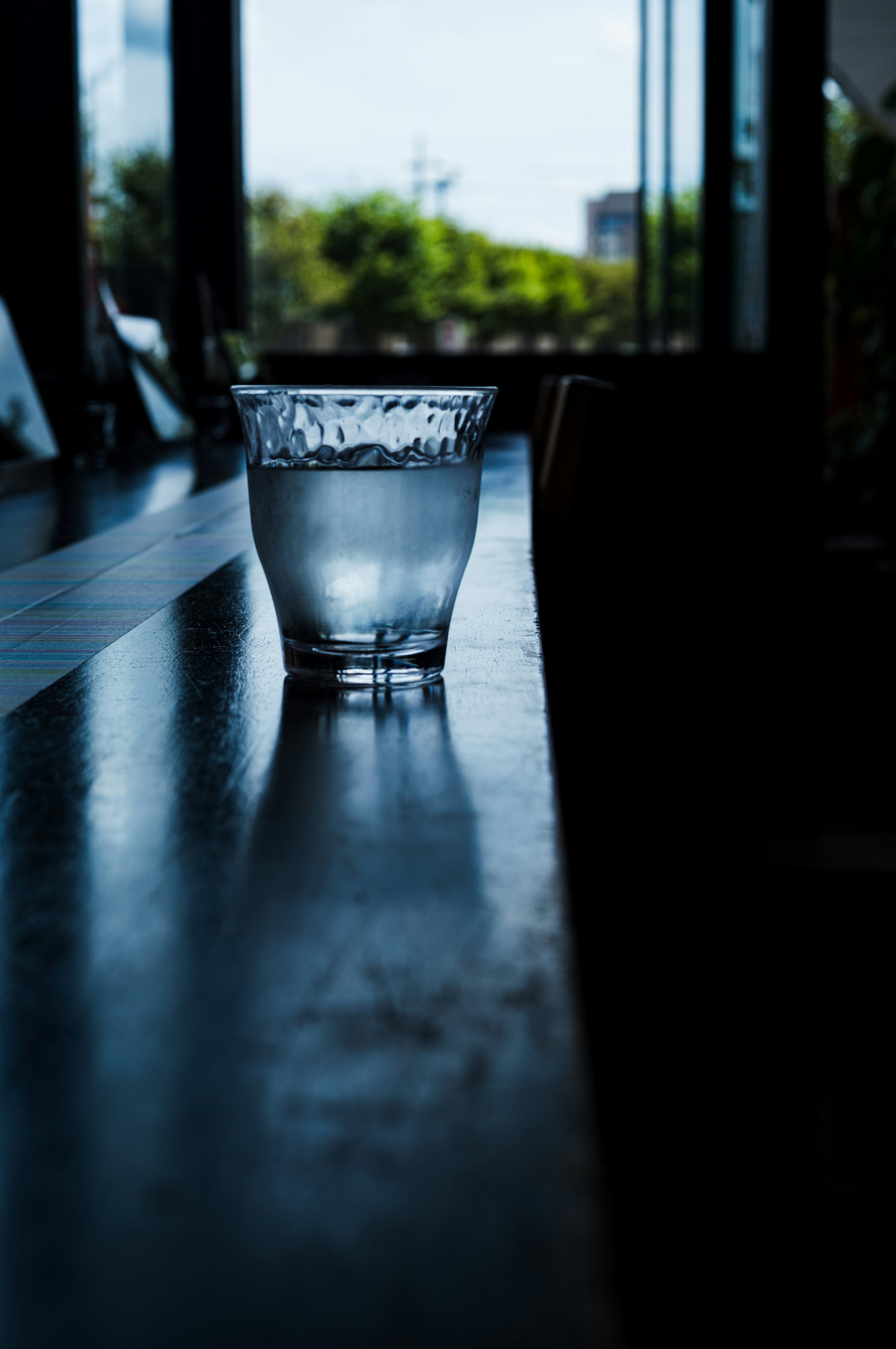 A clear glass of water on a table with soft shadows