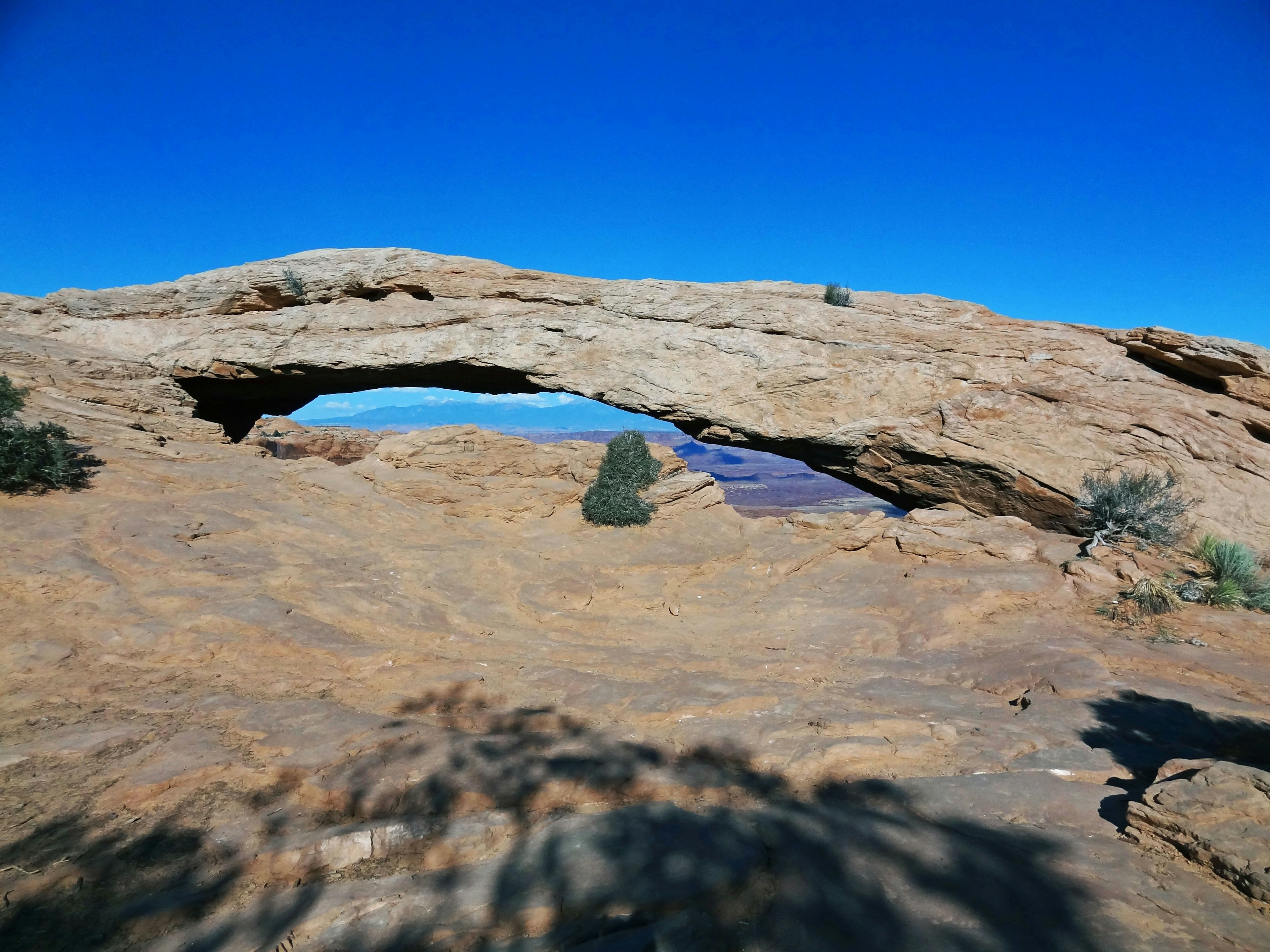 Arc rocheux naturel sous un ciel bleu avec un terrain rocheux environnant