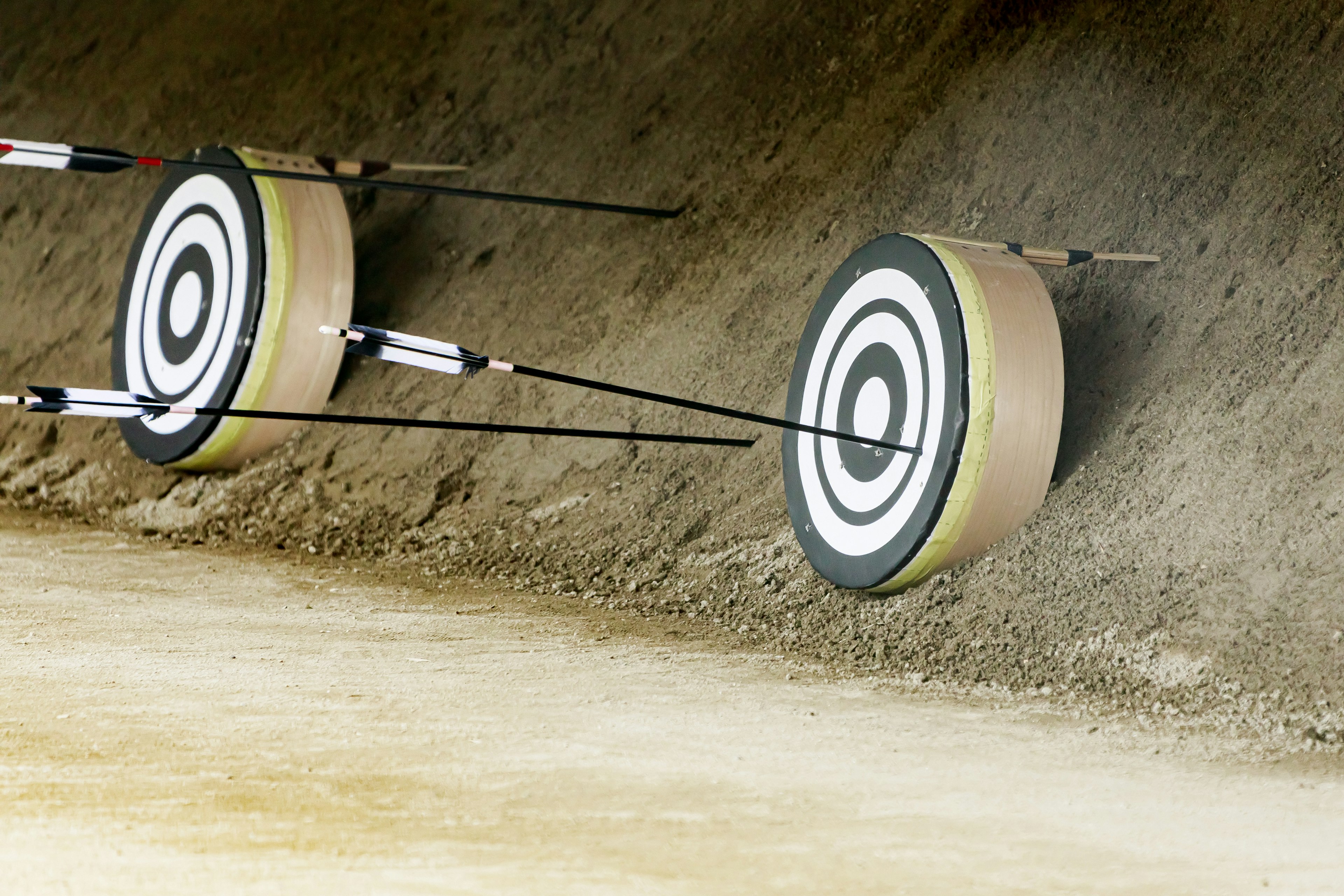 Two archery targets mounted on a dirt wall with arrows embedded