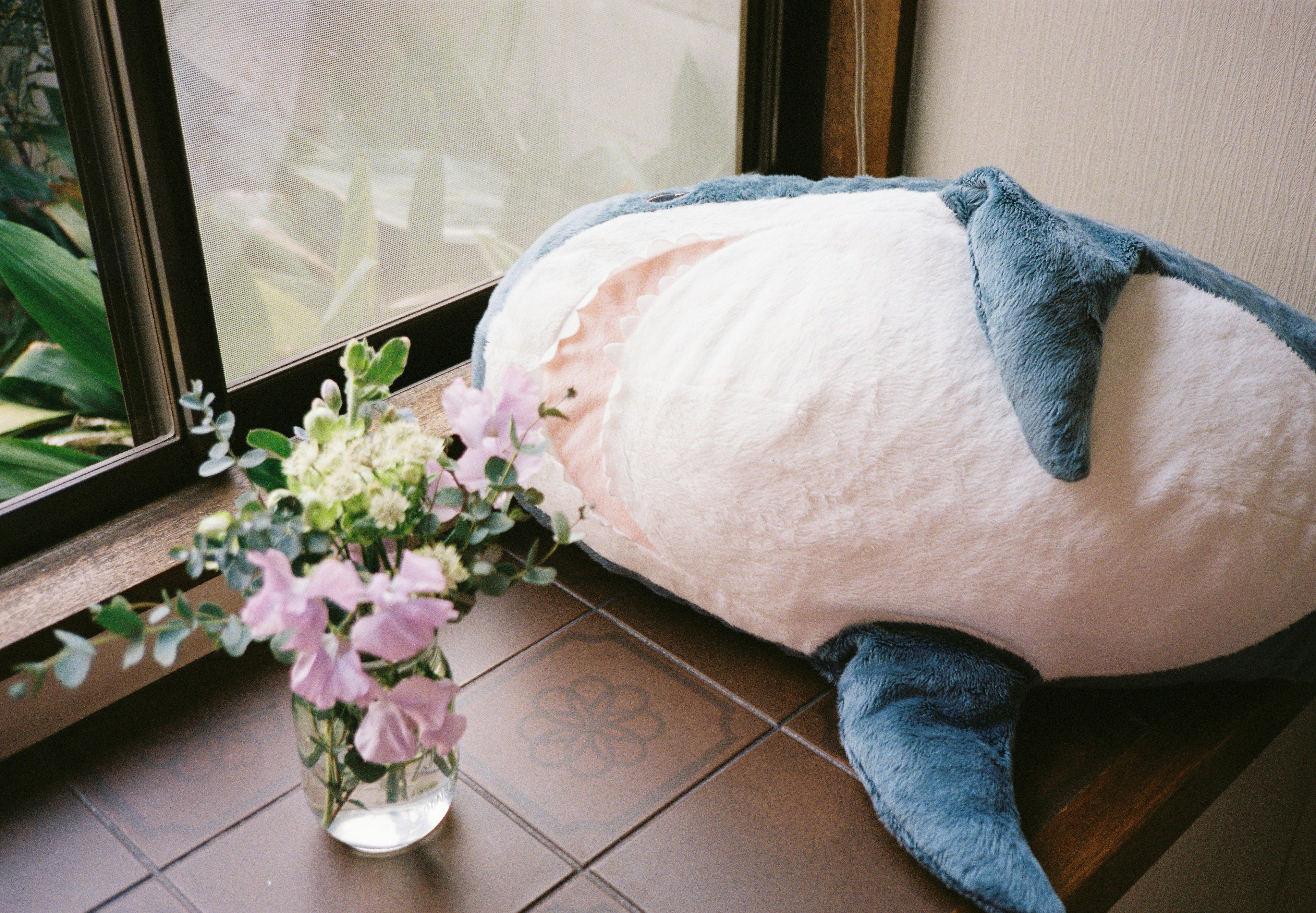 Whale plush toy and a vase of flowers on a windowsill