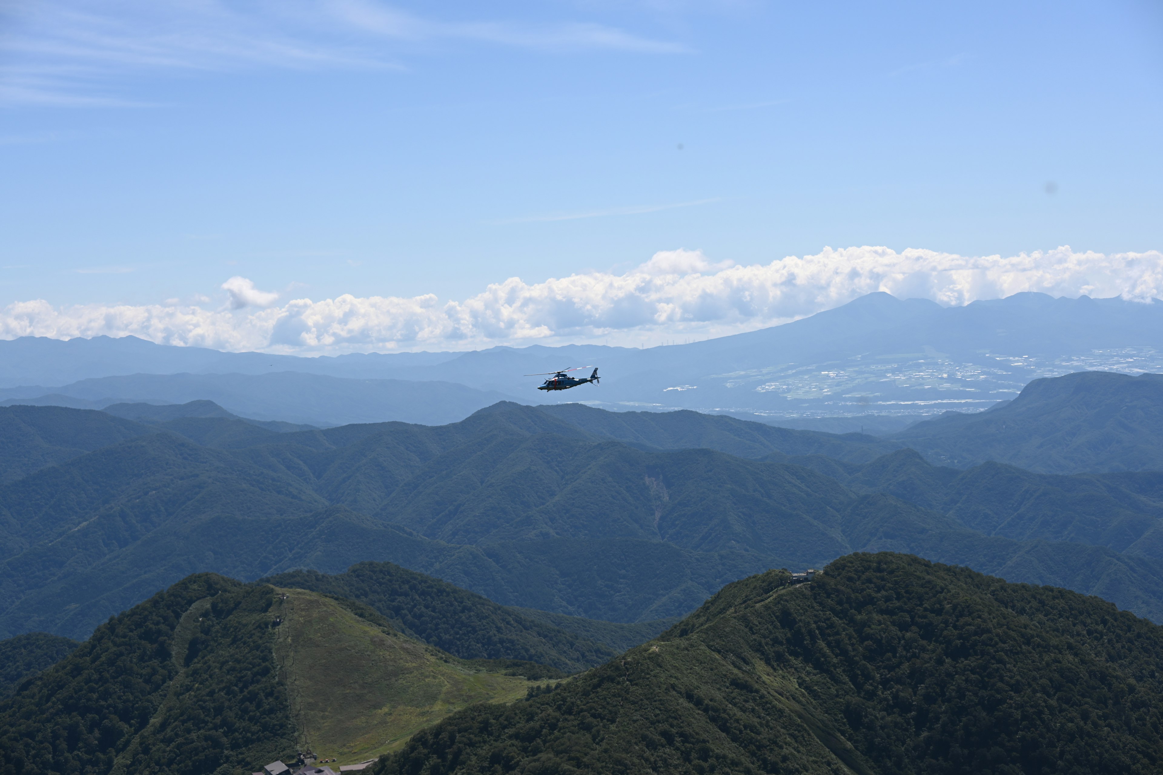 Helicopter flying over mountains with a blue sky