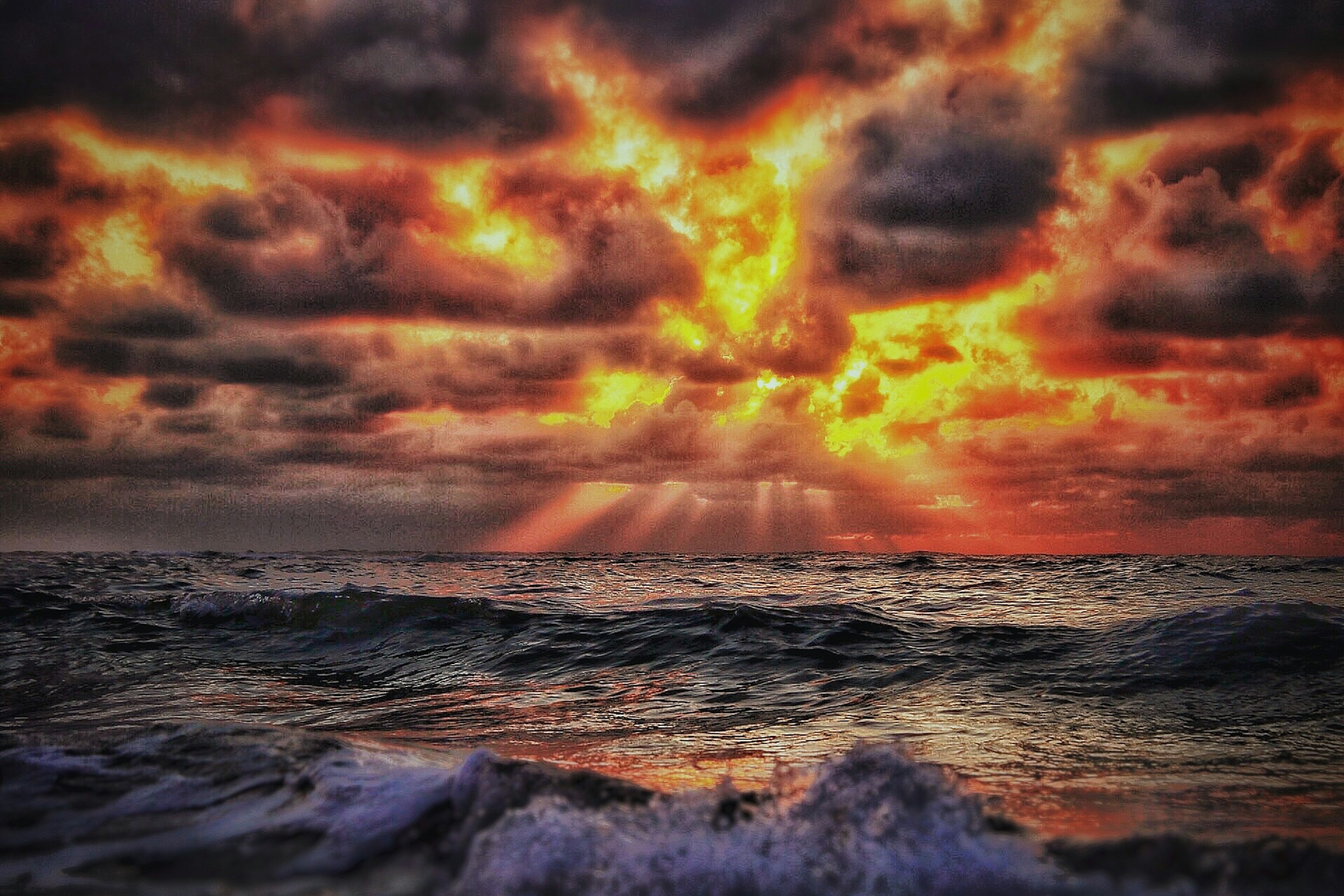 Impresionante paisaje marino al atardecer con nubes oscuras y rayos de luz naranja