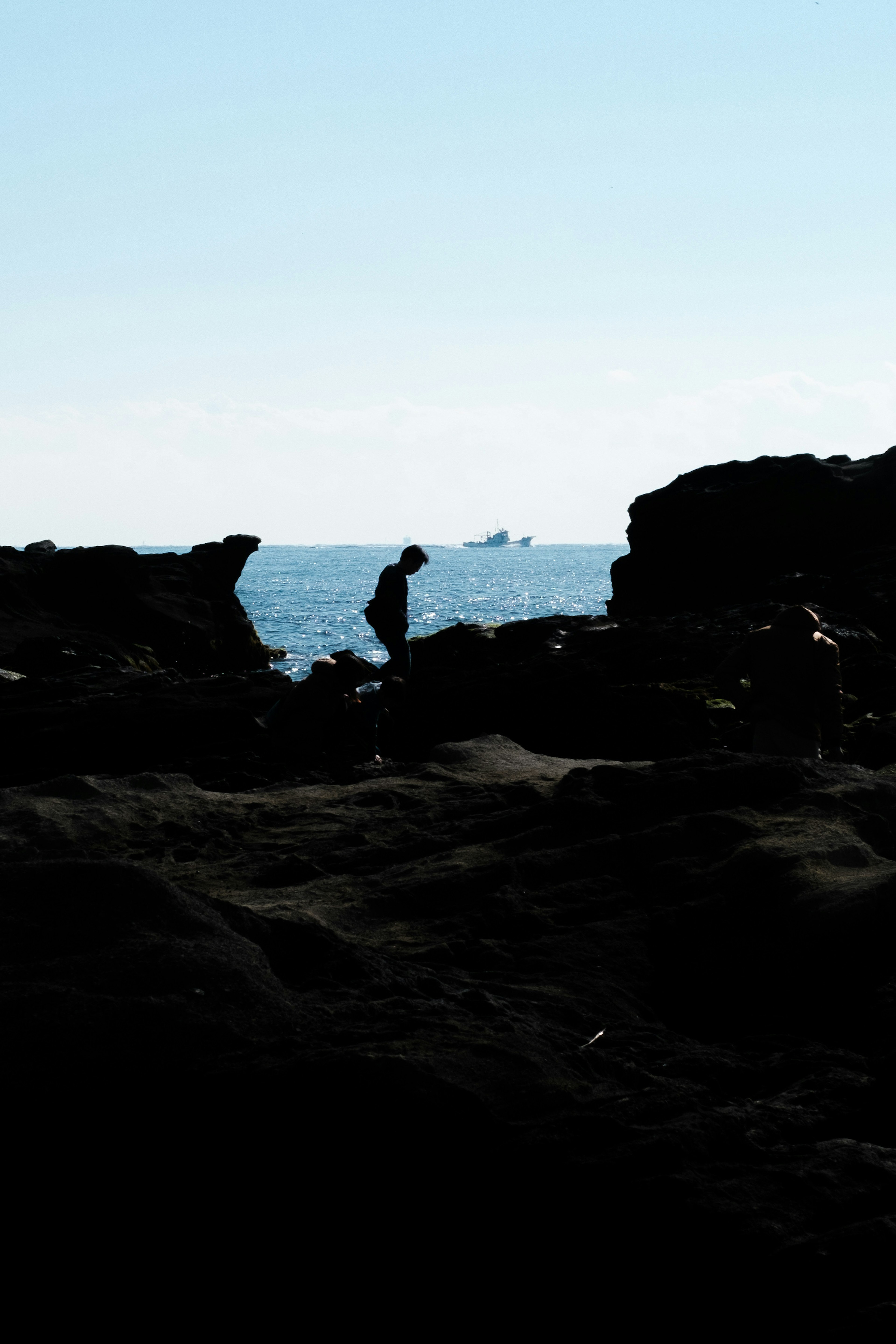 Siluet seseorang yang menjelajahi batuan dekat laut