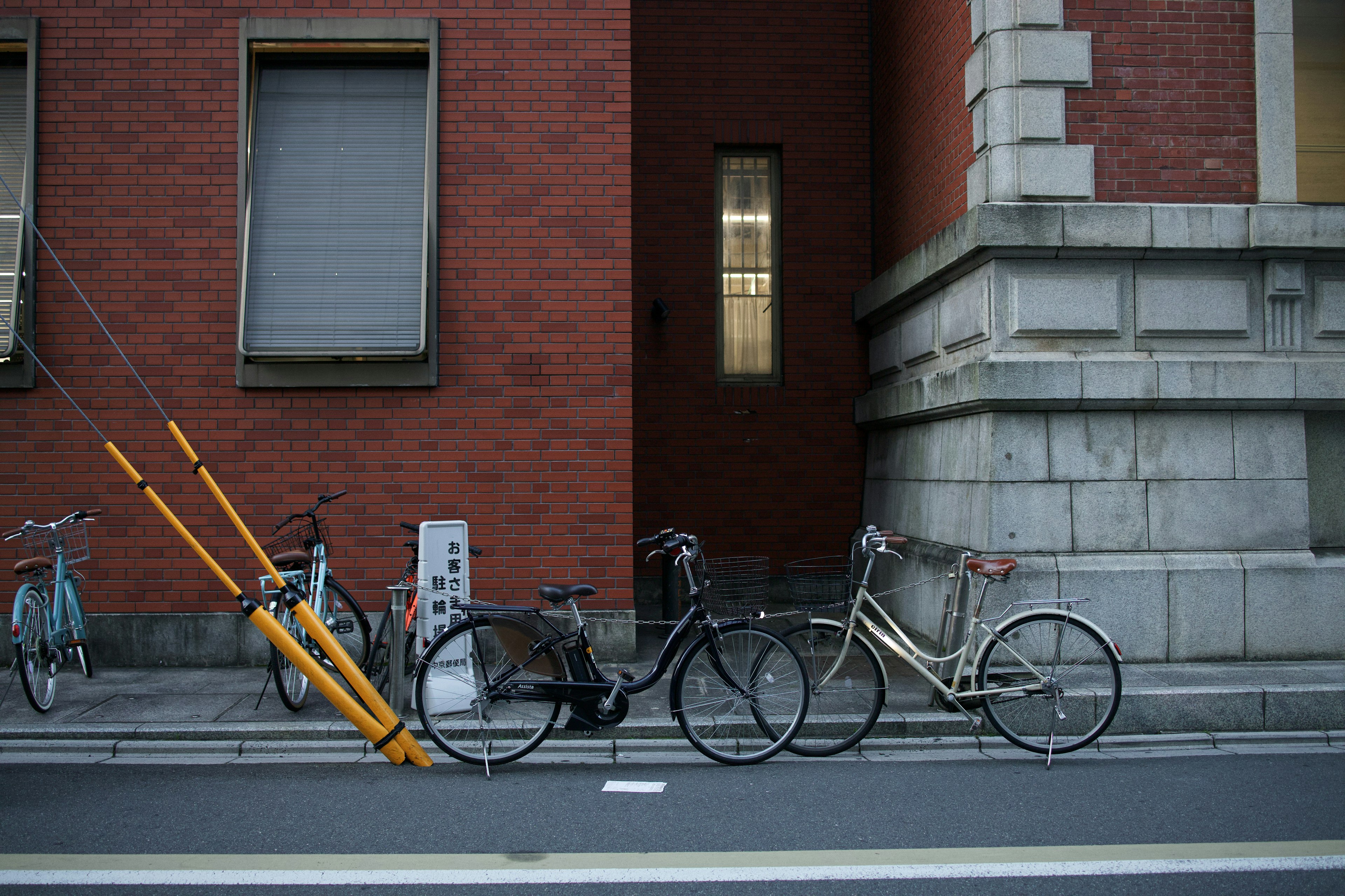 赤レンガの建物の前に停められた自転車と黄色のポール