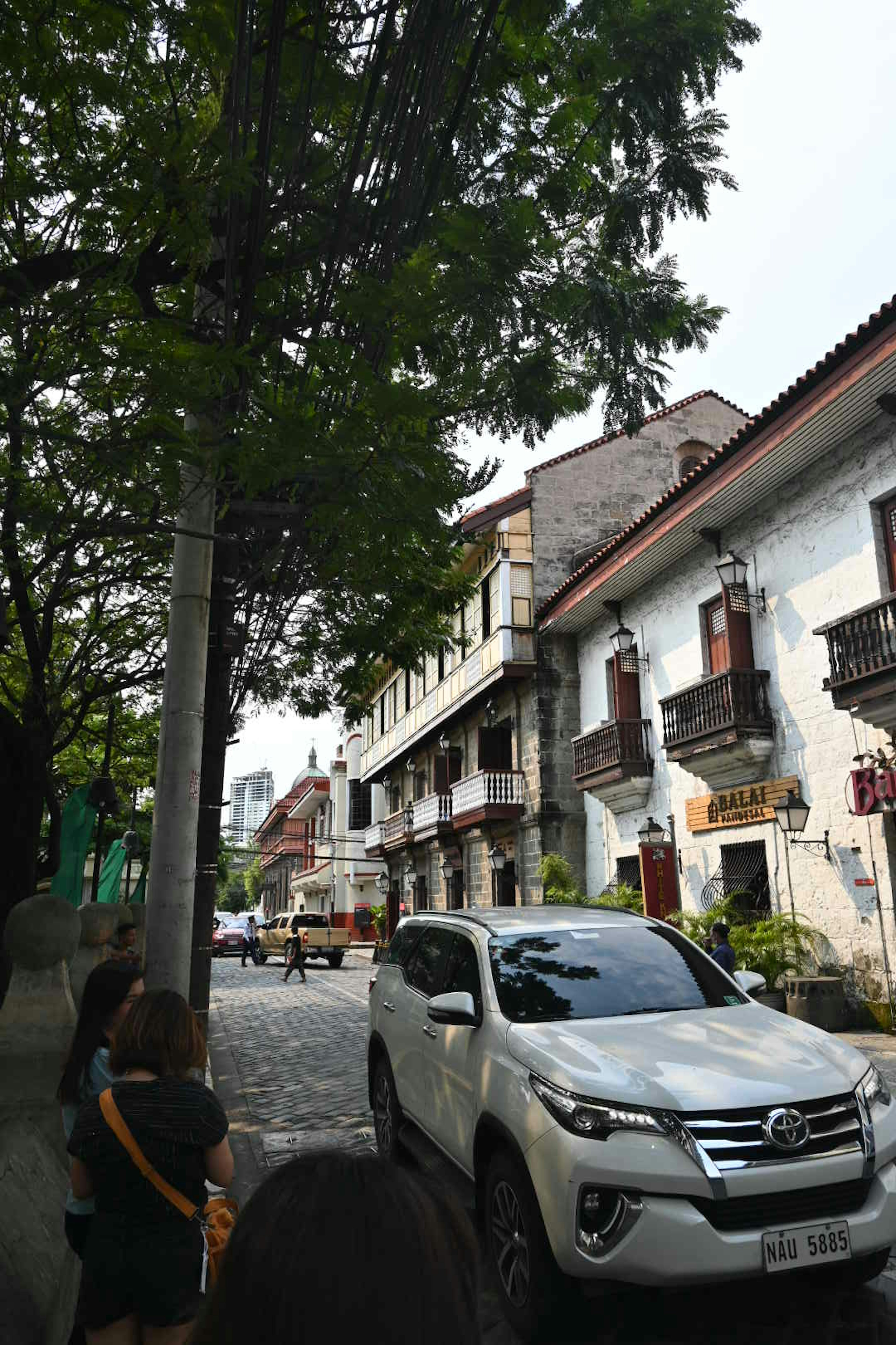 Street view featuring a white car and historical buildings