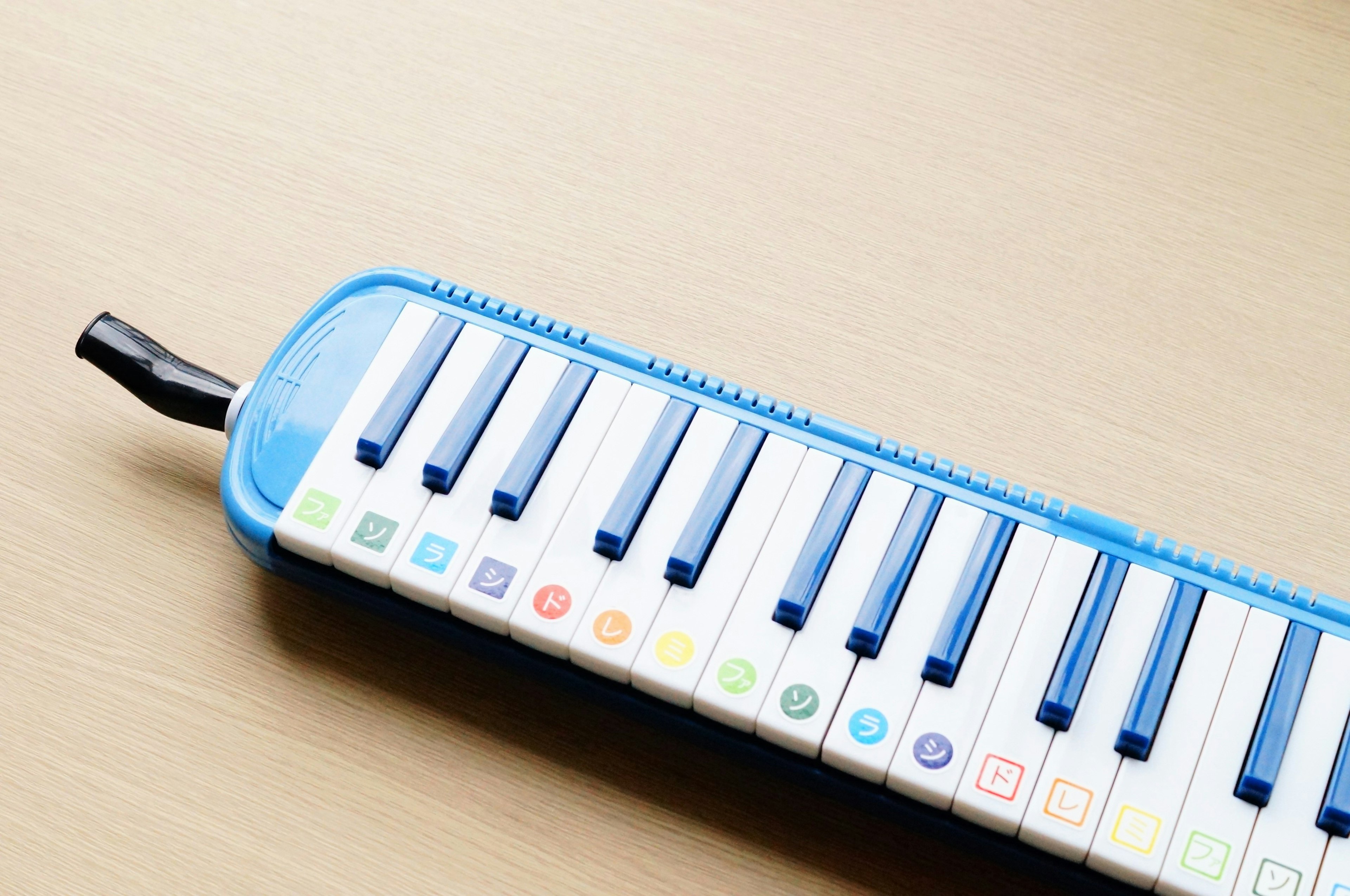 Melodica màu xanh với phím trắng đặt trên bàn gỗ