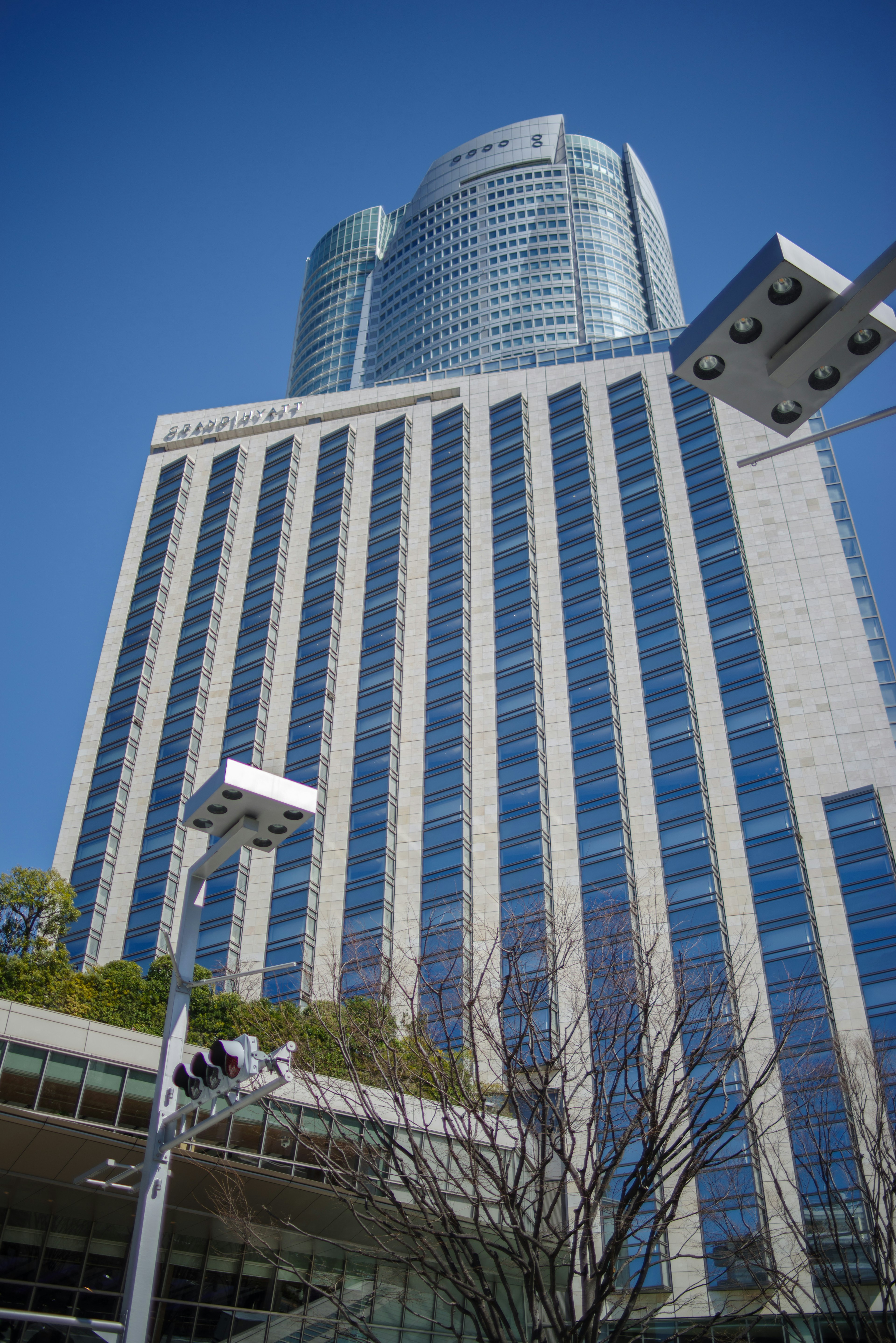 Image captured from below a skyscraper featuring reflective glass facade and clear blue sky