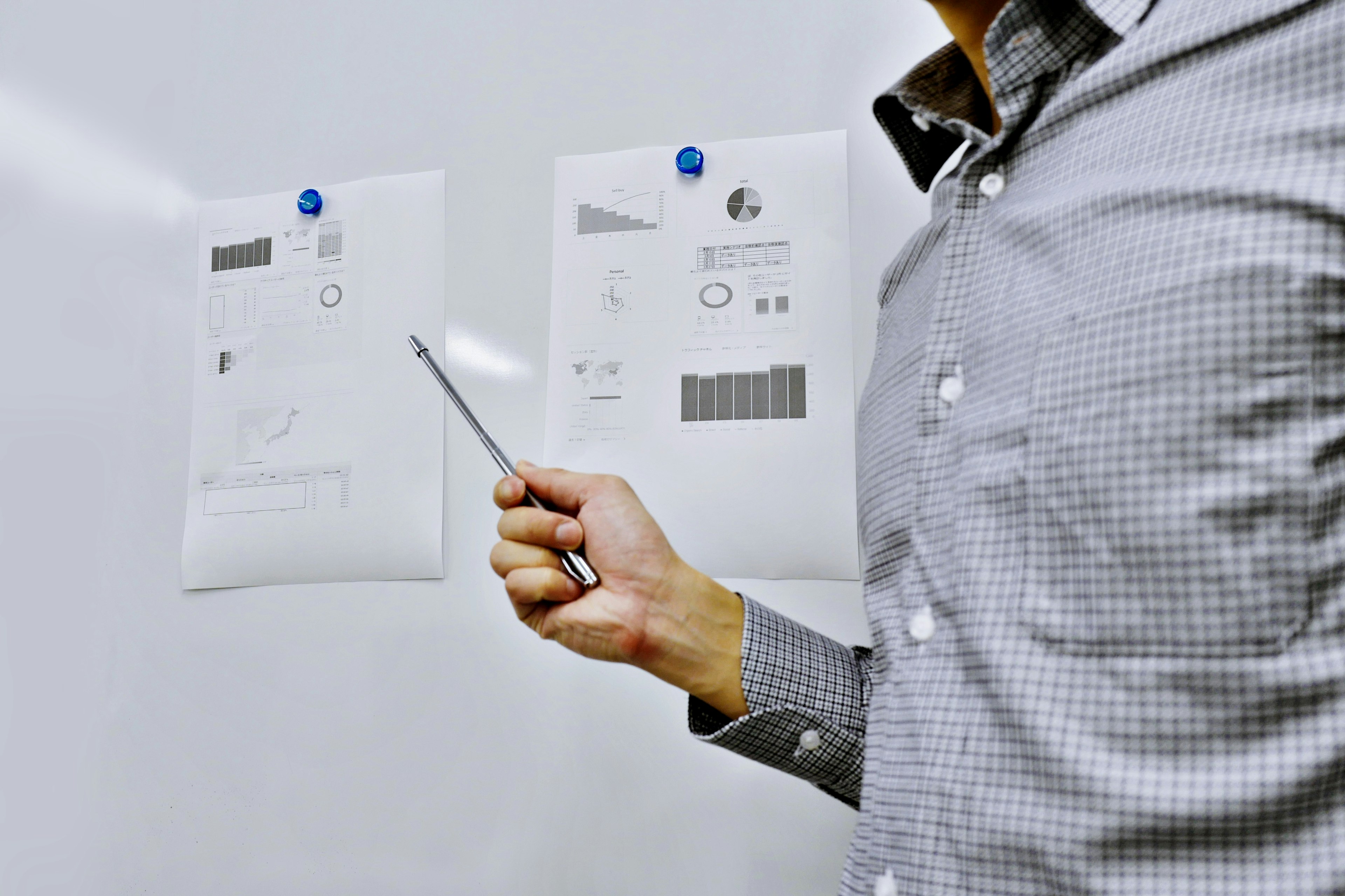 Un homme présentant et pointant des documents épinglés sur un tableau blanc