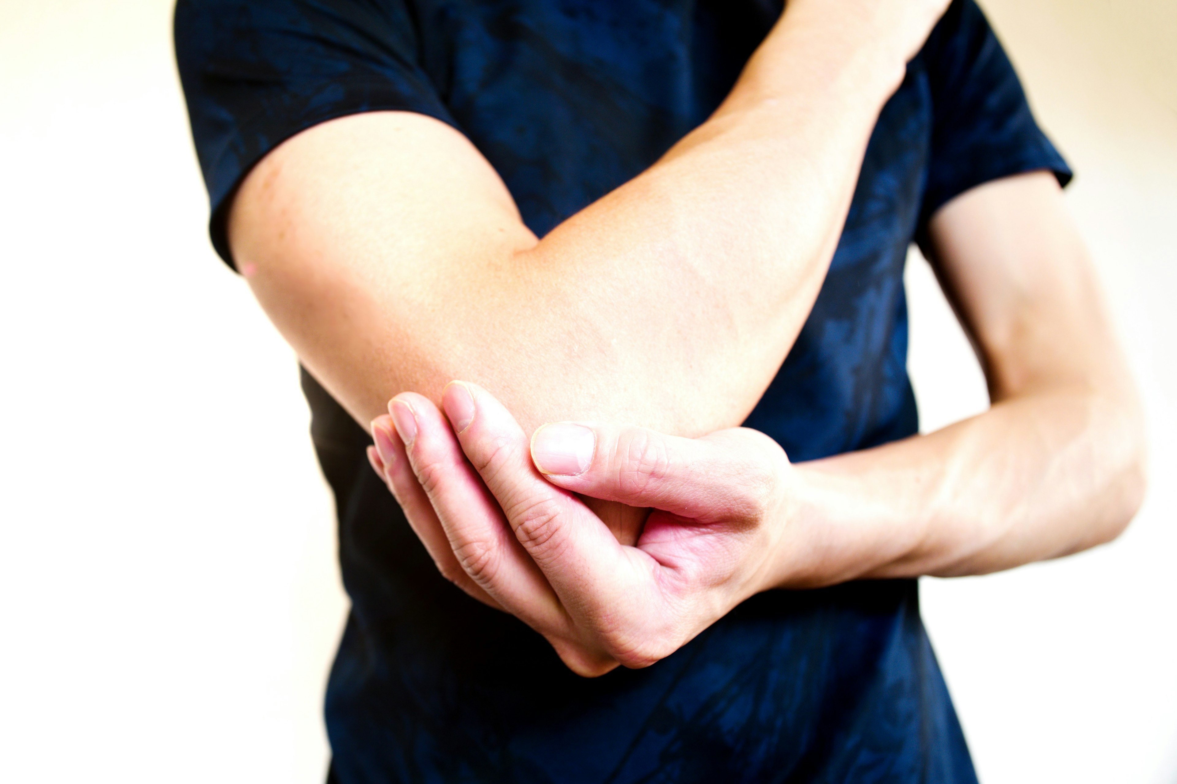 Close-up of a man's hand holding his elbow