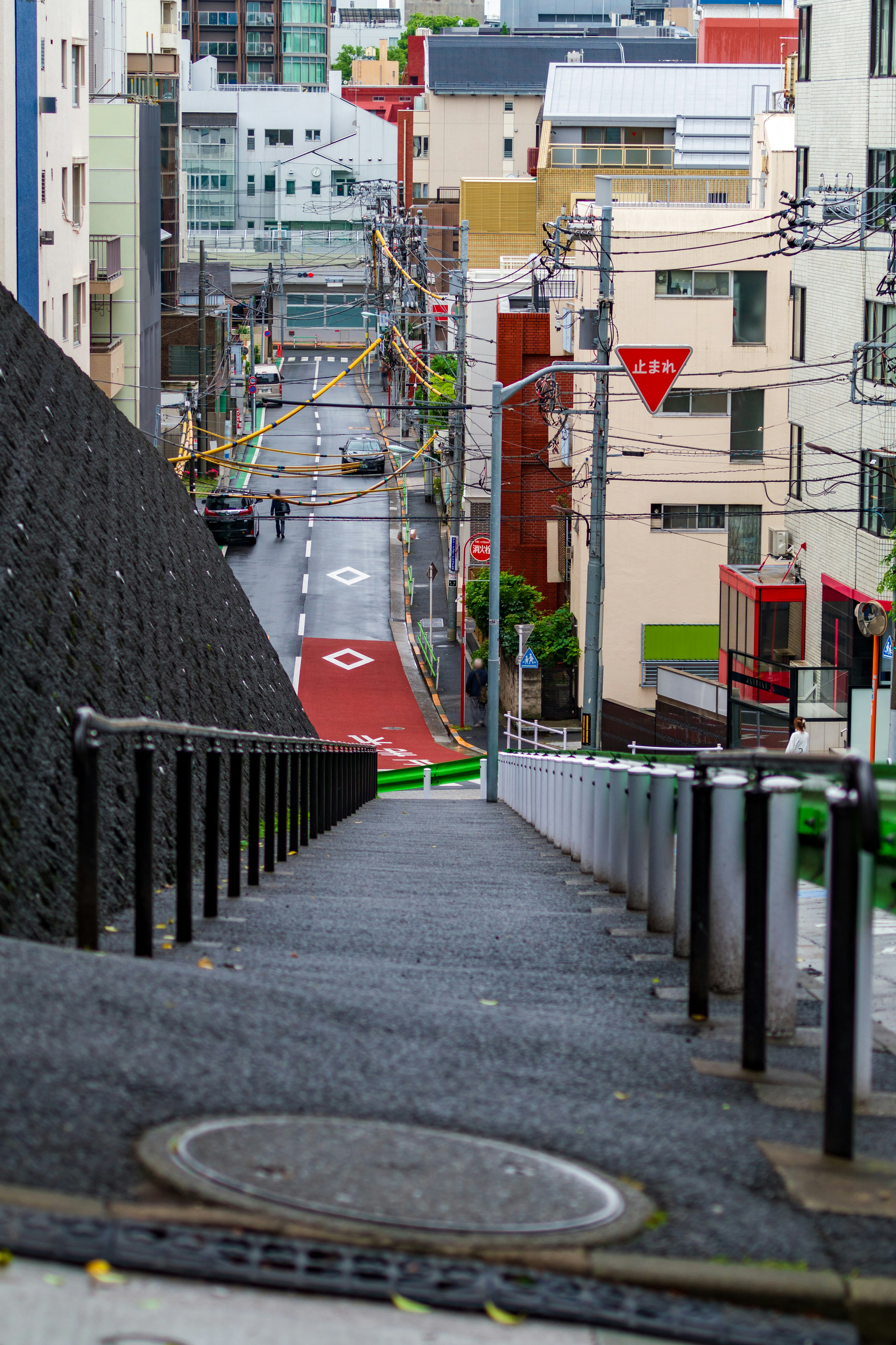 傾斜した歩道が見える都市の風景で、赤い道路と建物が並んでいる