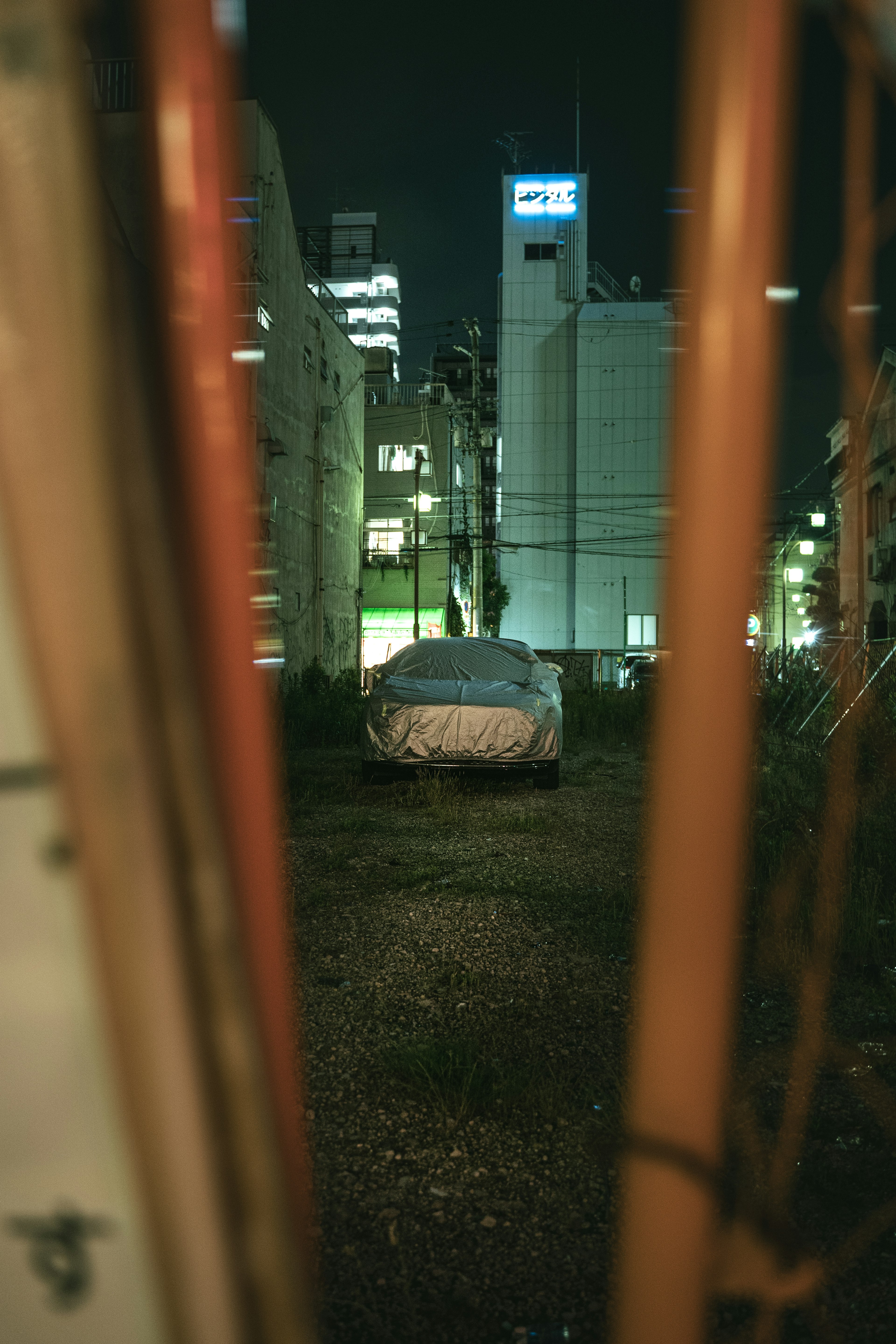 An old car hidden in an empty lot in the city at night