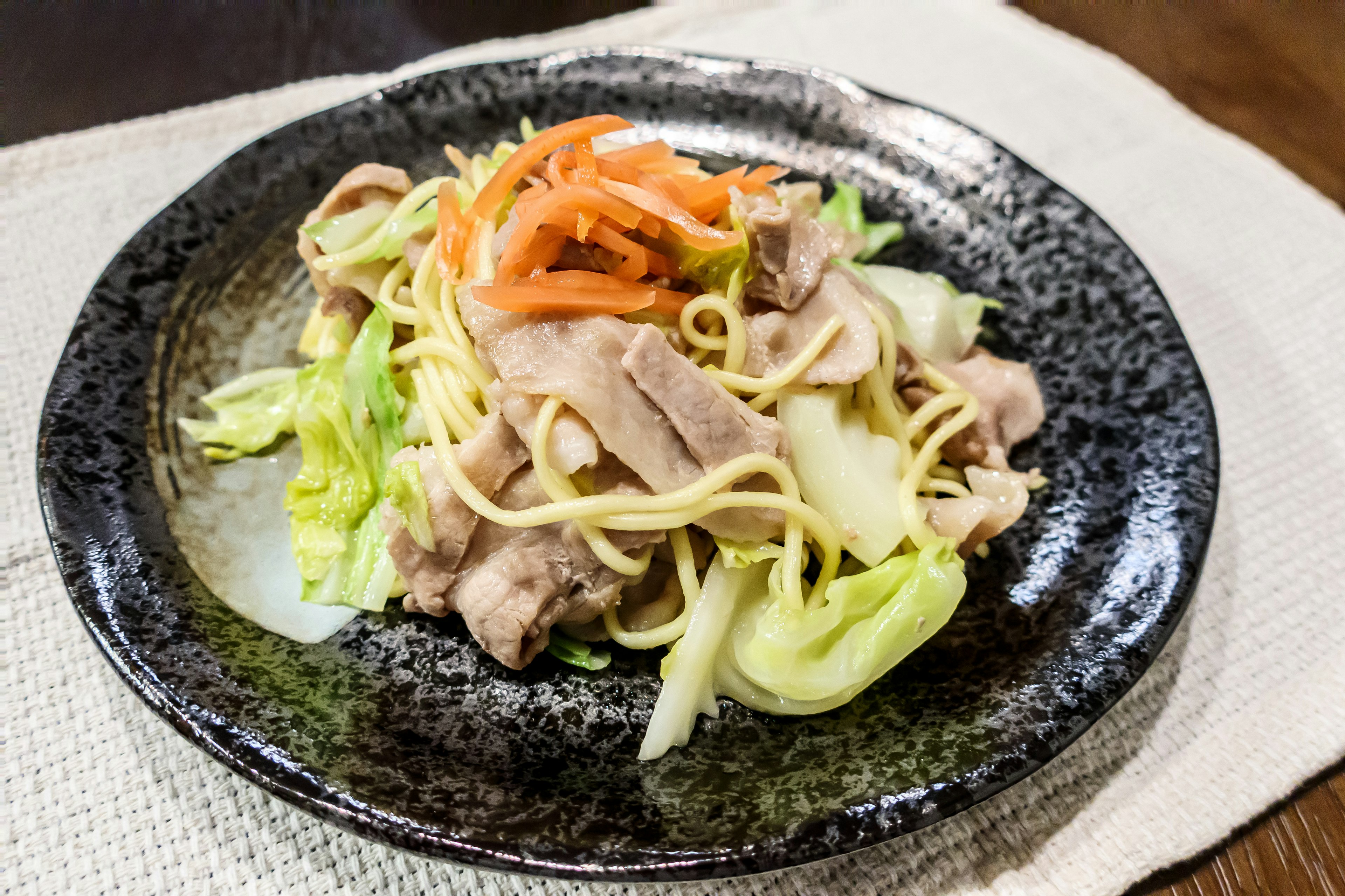 Plate of stir-fried noodles topped with cabbage and carrots