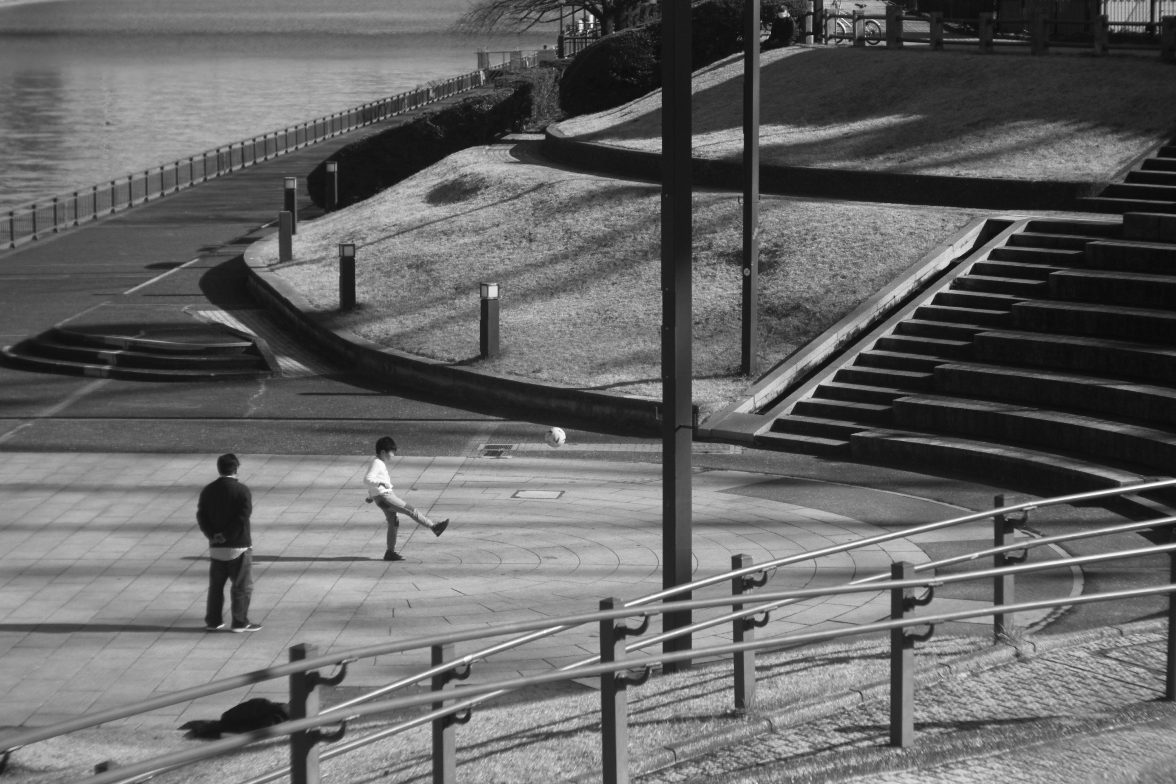 Photo en noir et blanc d'un enfant jouant dans un parc avec un adulte observant