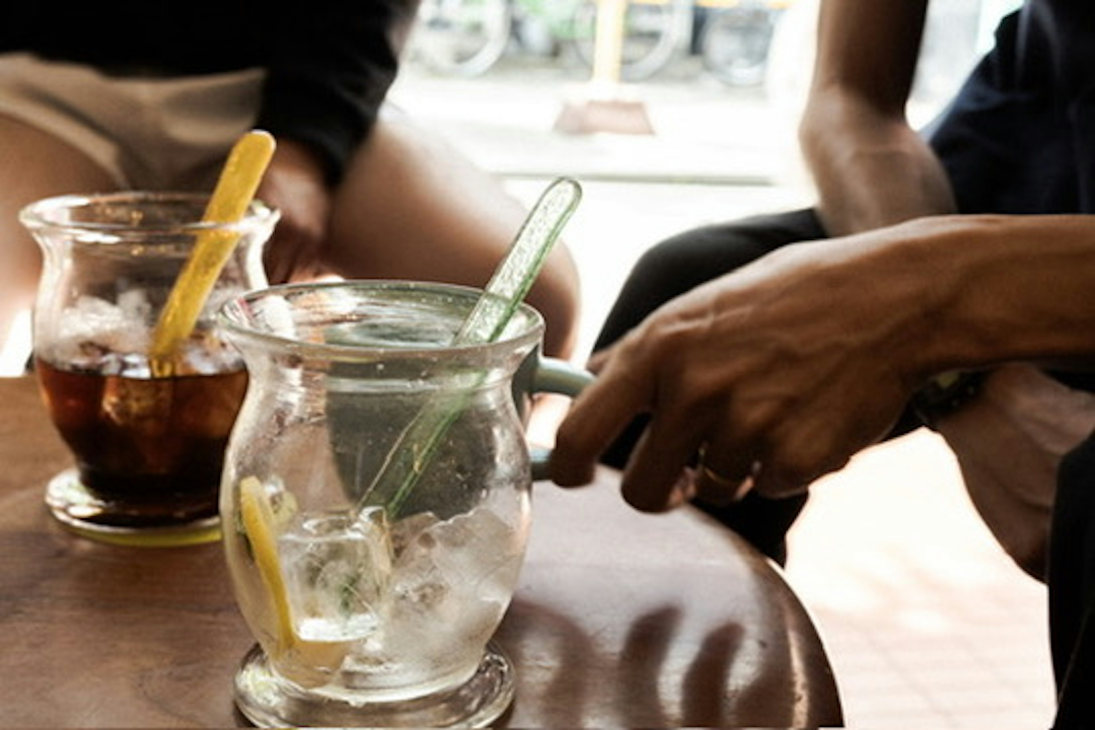 Primer plano de bebidas en una mesa con un vaso transparente con hielo y limón