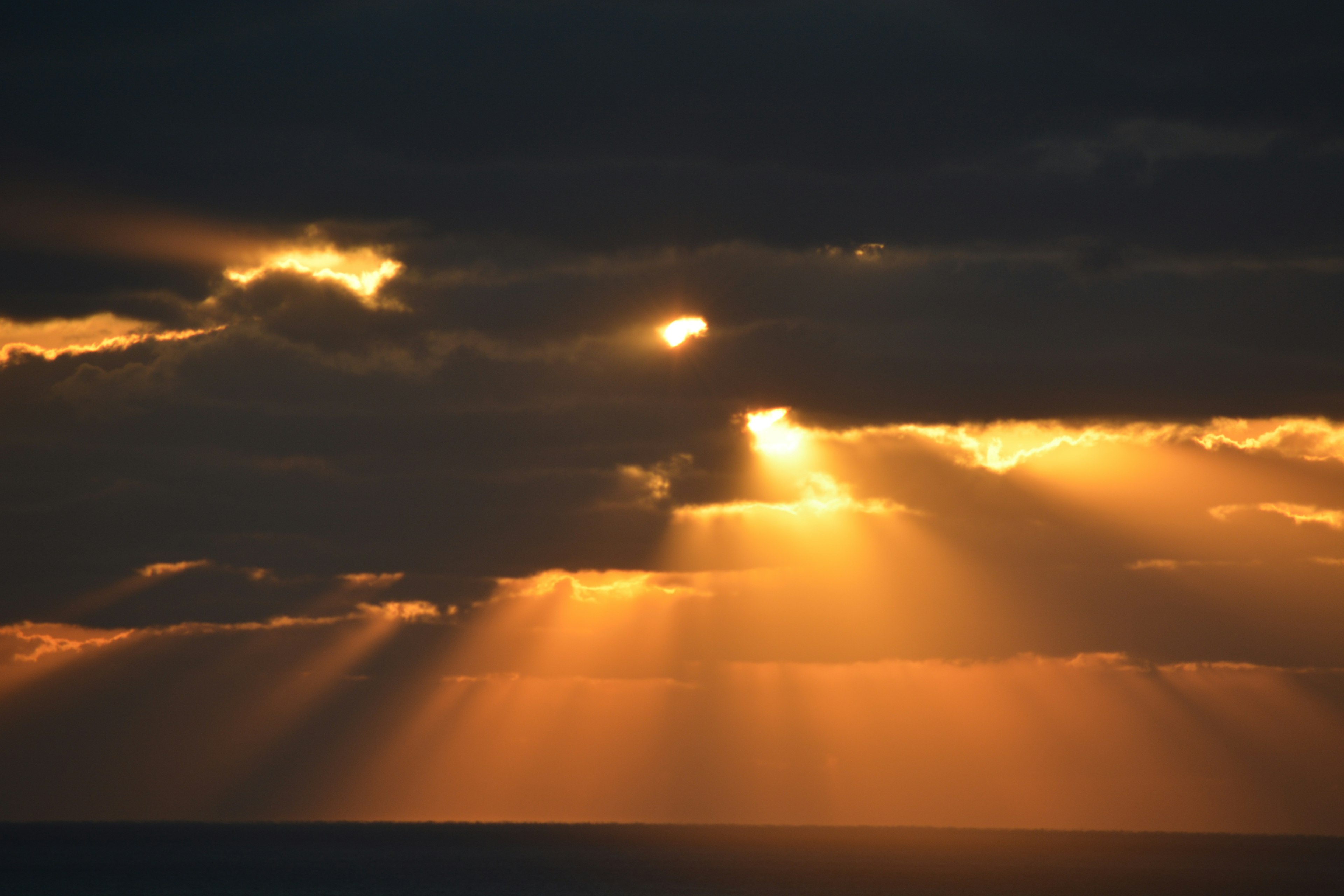 Rayons de soleil perçant des nuages sombres au coucher du soleil