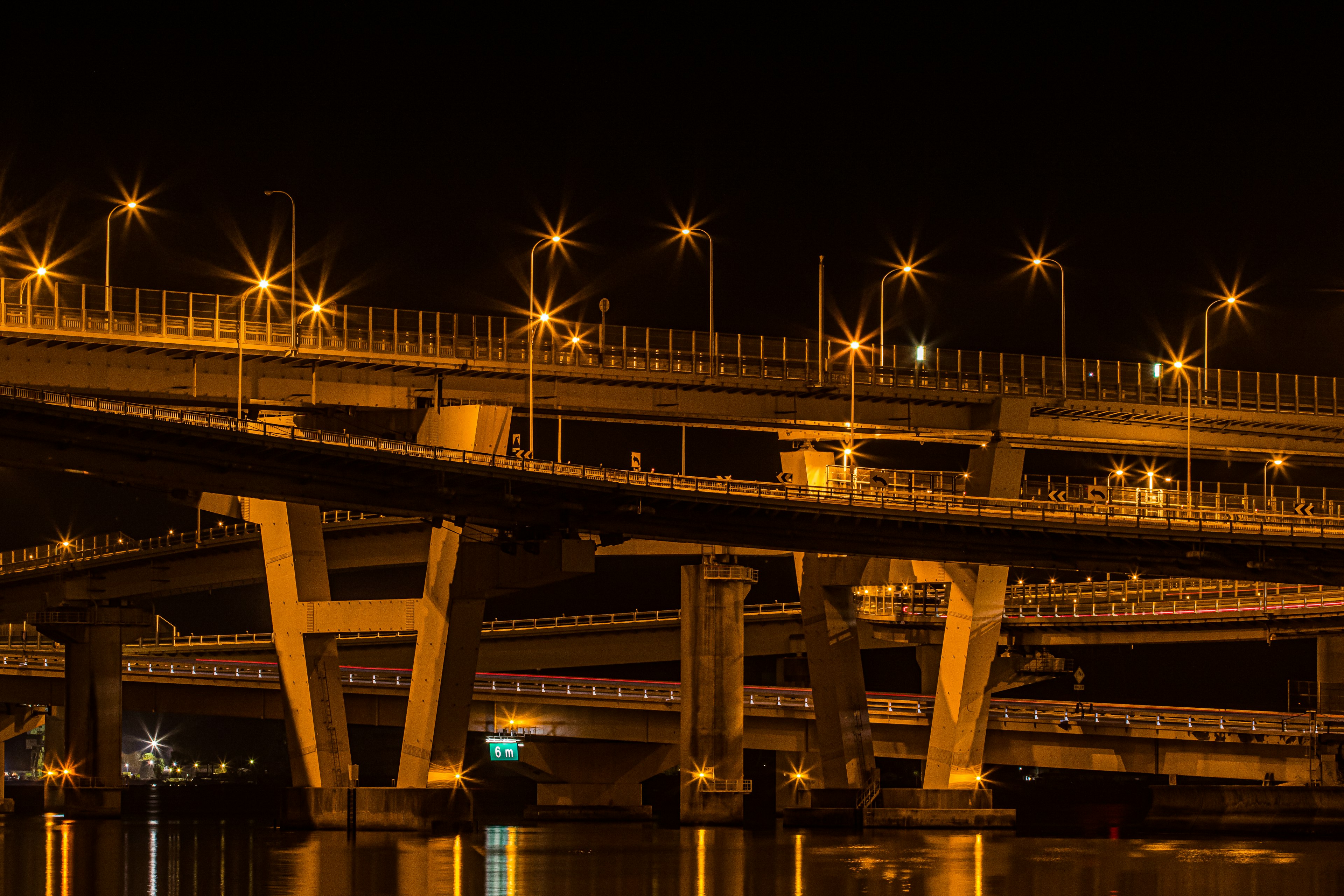 Paso elevado iluminado de noche con reflejos en el agua