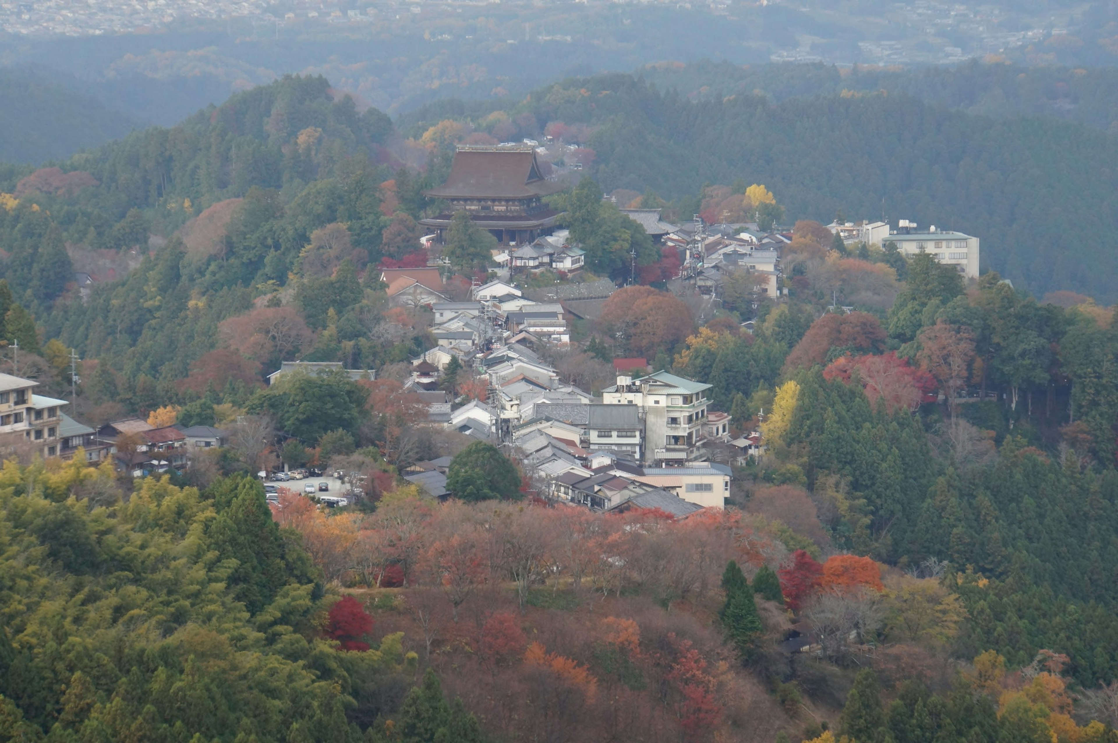 ทิวทัศน์ที่สวยงามของเมืองบนเนินเขาพร้อมใบไม้ฤดูใบไม้ร่วงและวัด