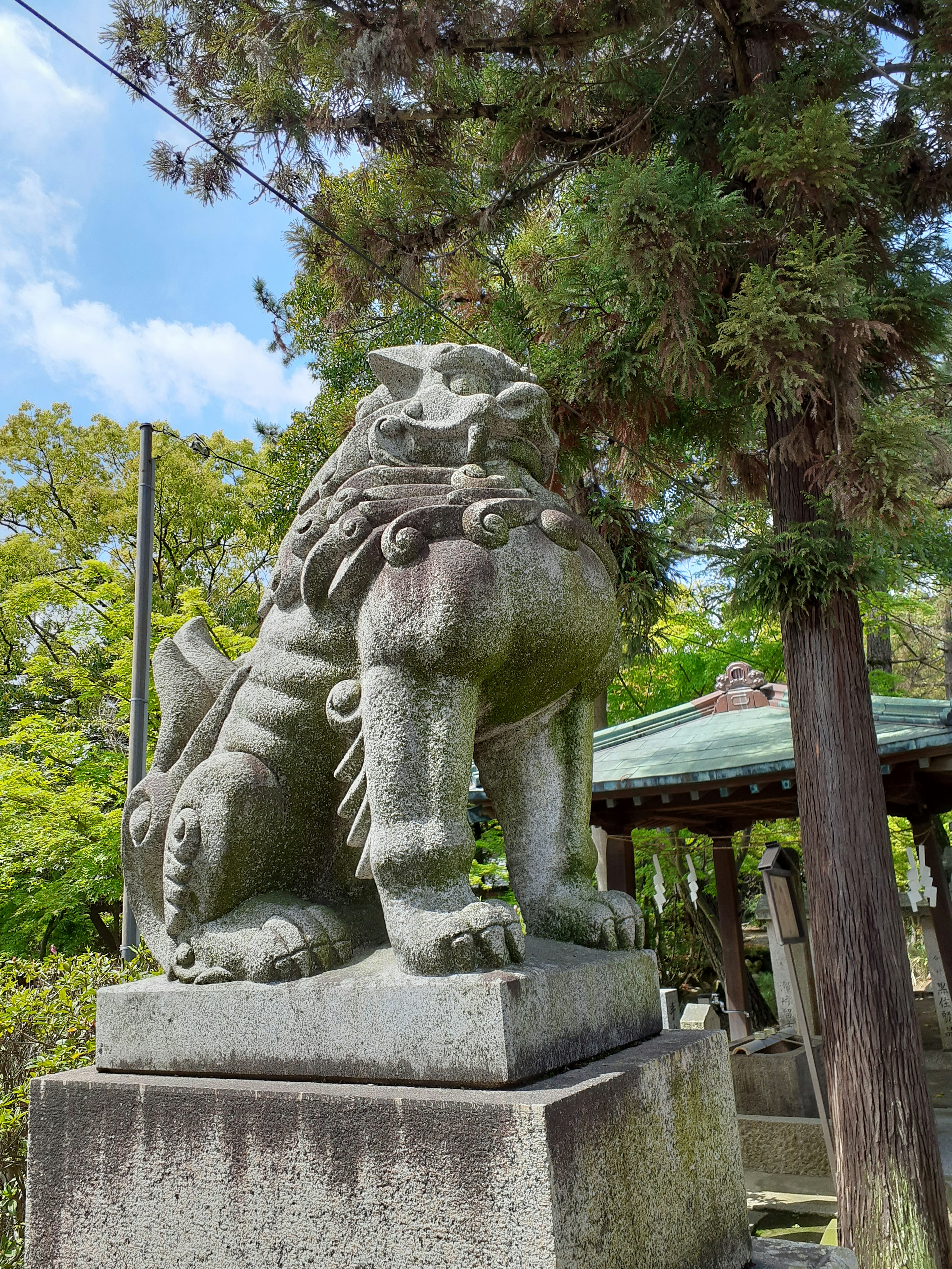 Stone guardian lion statue standing amidst lush greenery