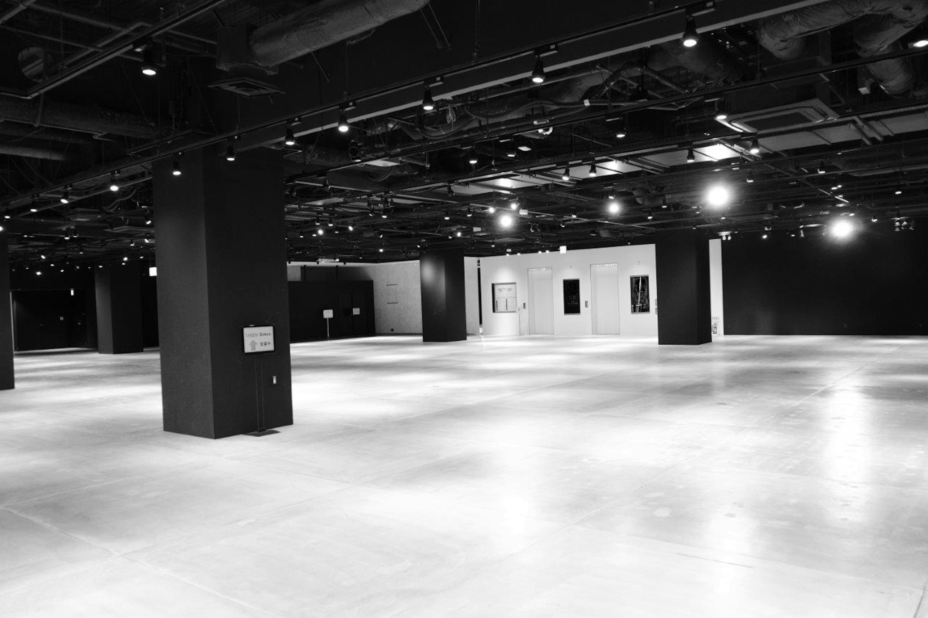 Spacious interior with black walls and white floor illuminated by bright ceiling lights