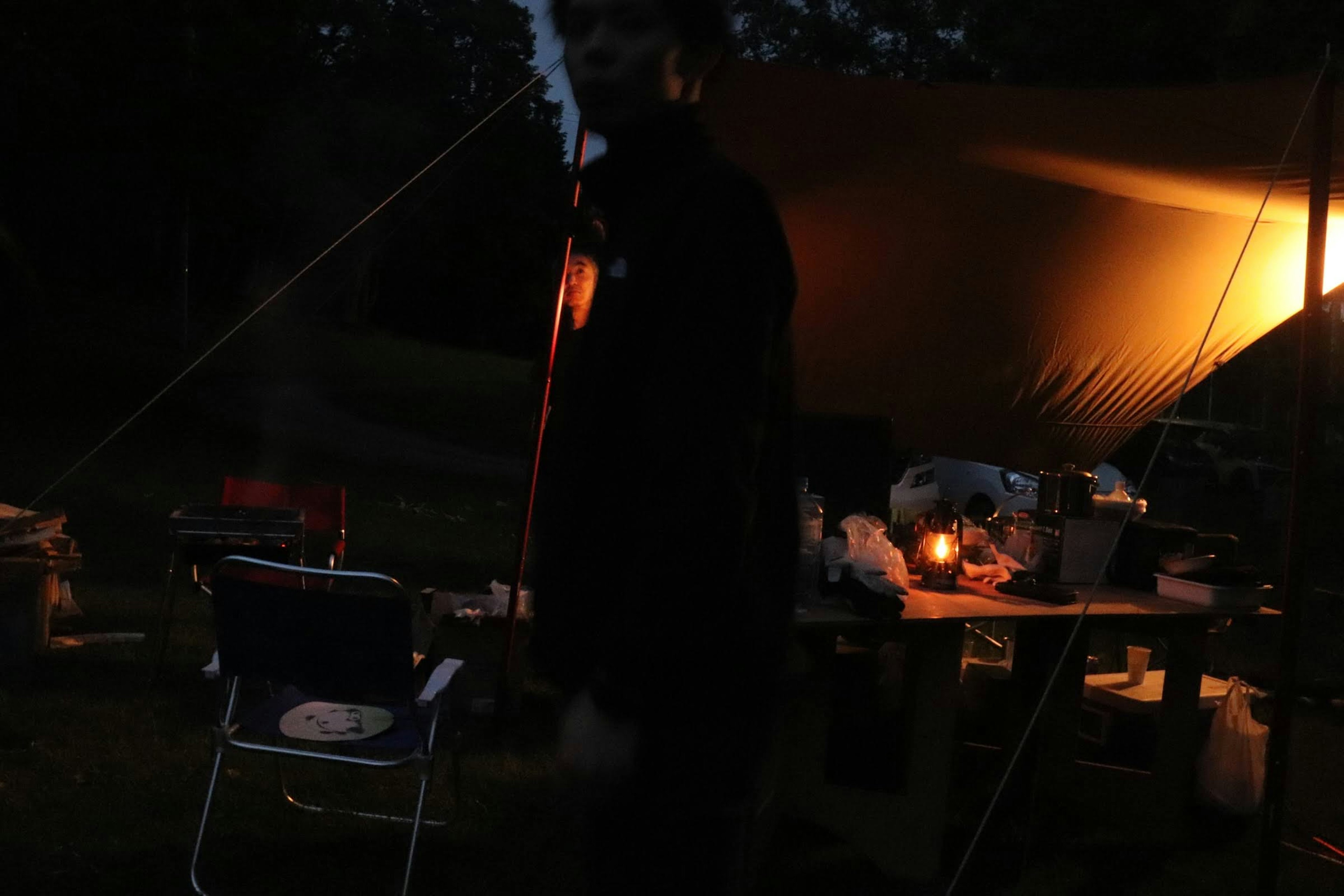 Dark campsite featuring a tent and a lamp