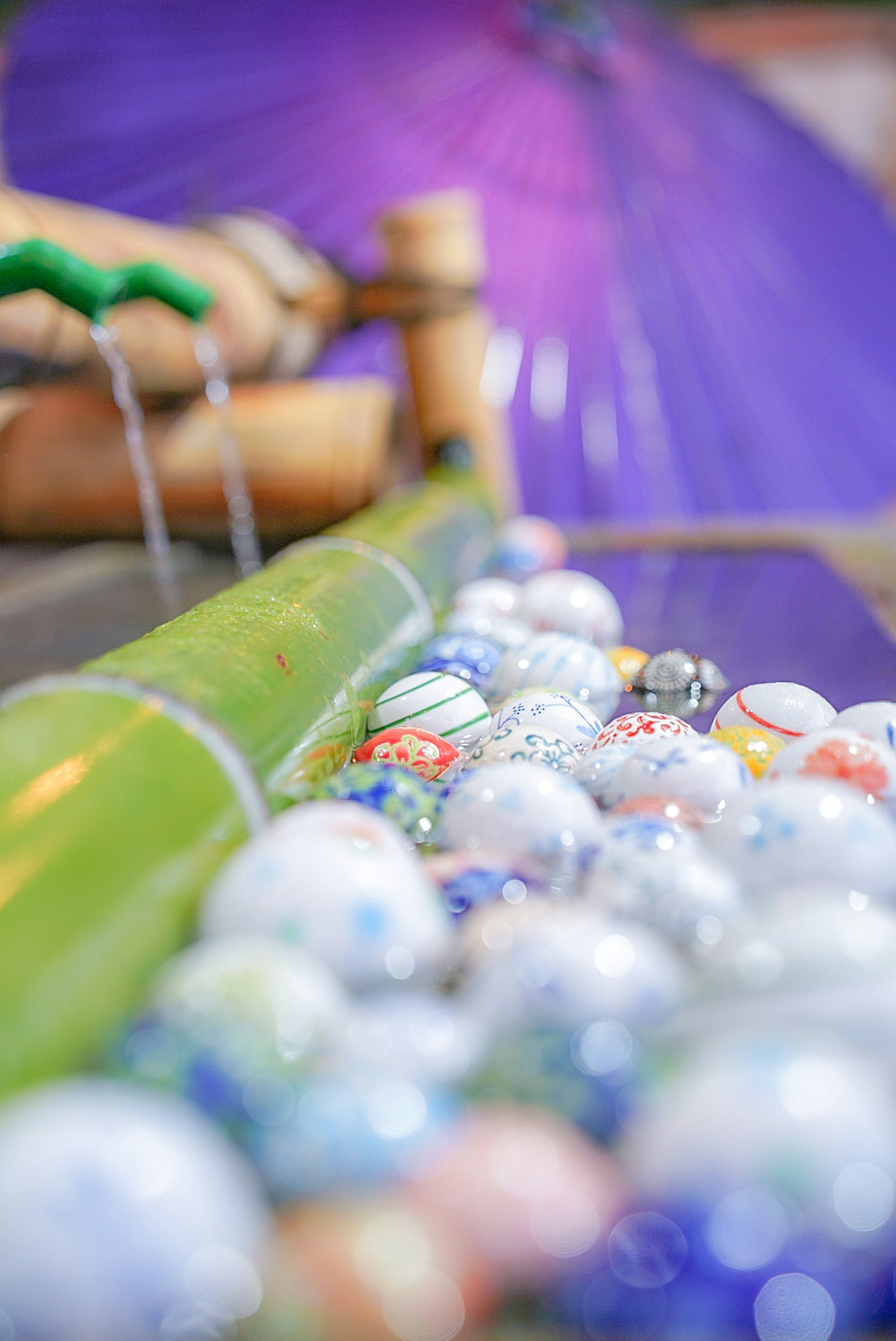 Bamboo fountain with colorful beads and purple umbrella