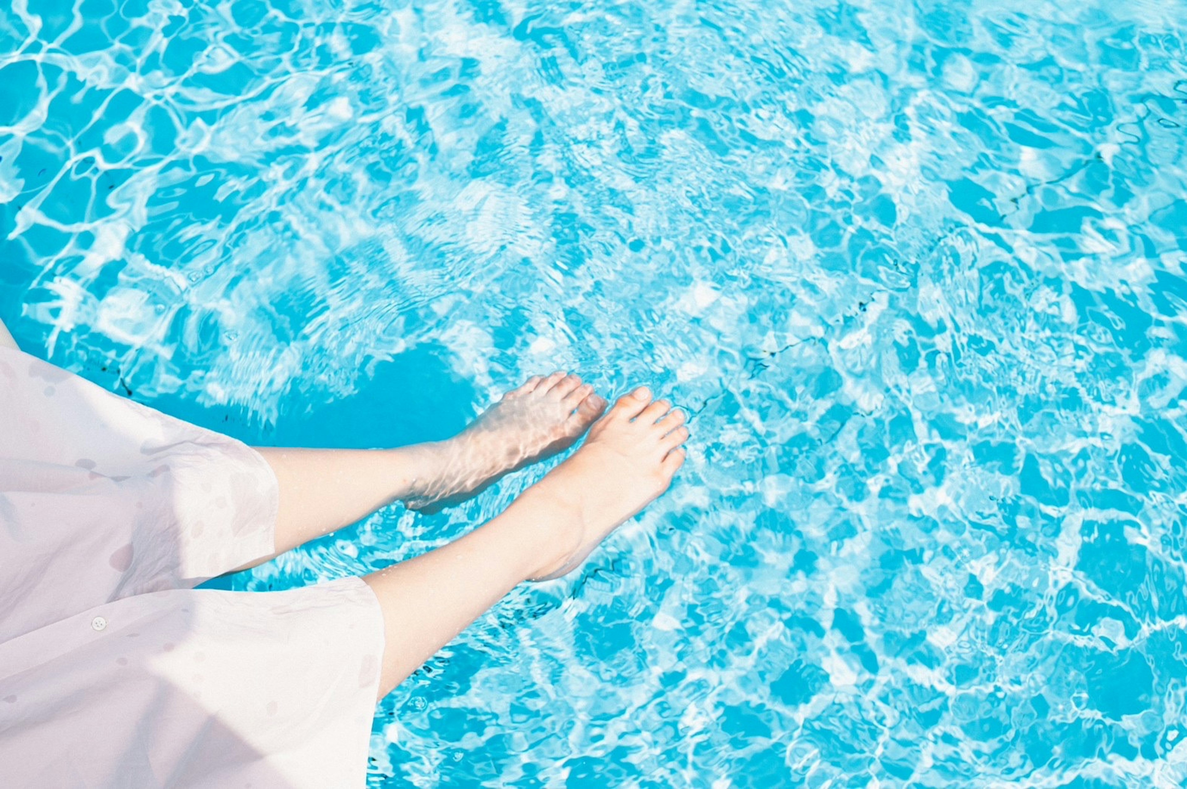 Feet submerged in clear blue pool water