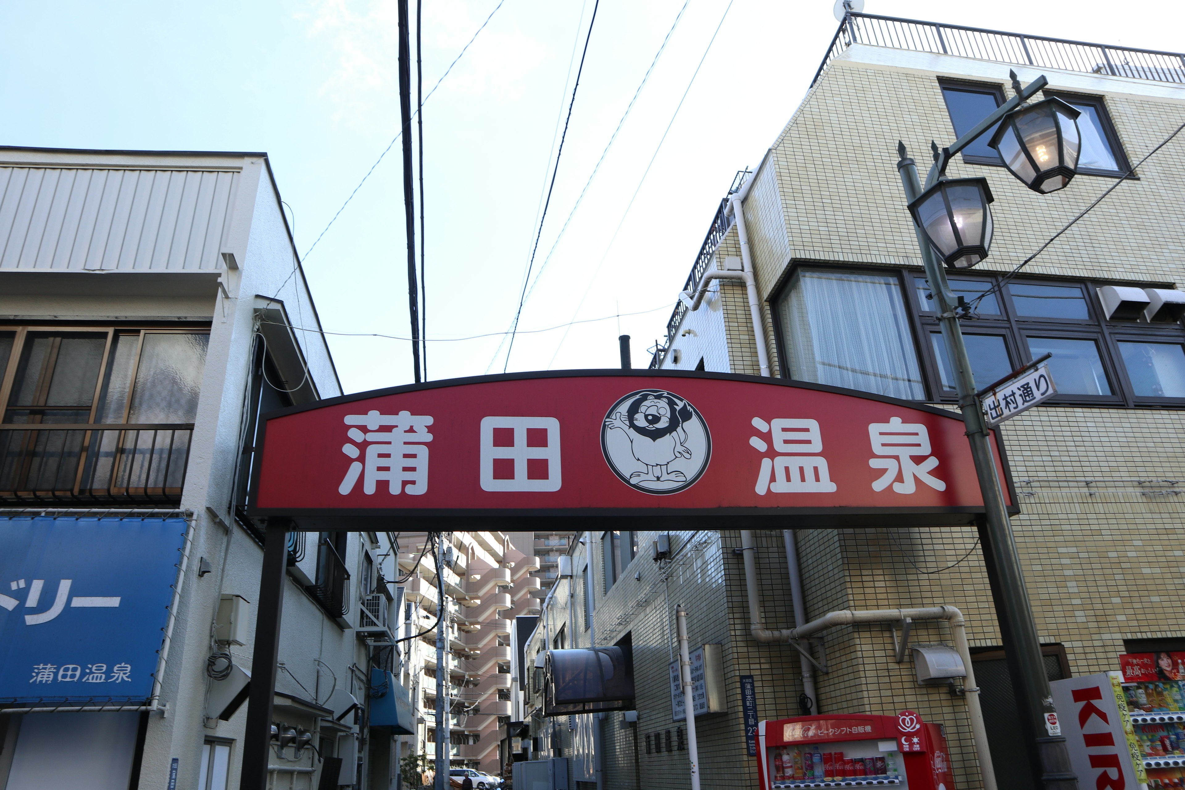 蒲田温泉の赤い看板と周囲の建物の風景