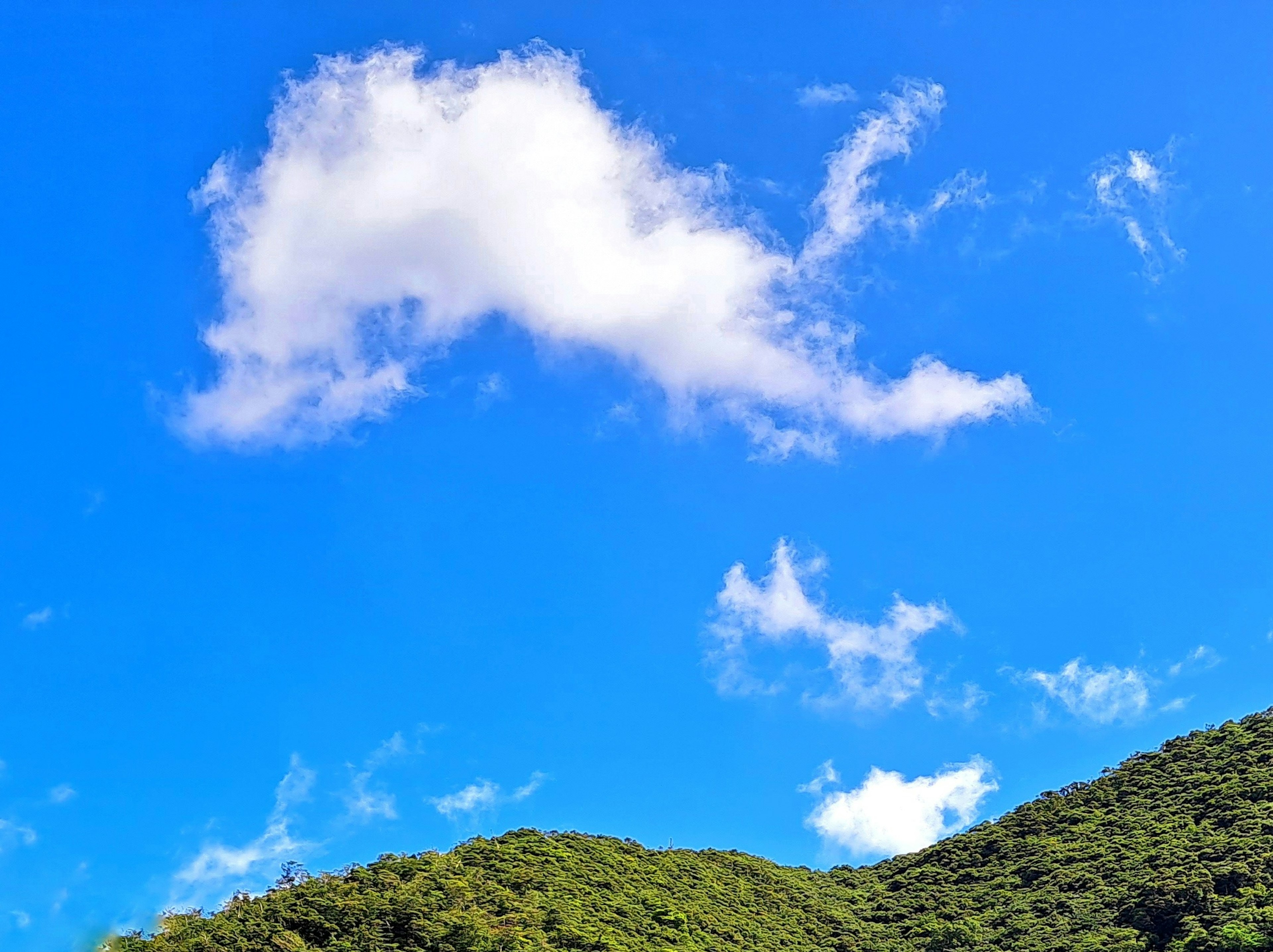 Un paisaje con cielo azul, nubes blancas y colinas verdes