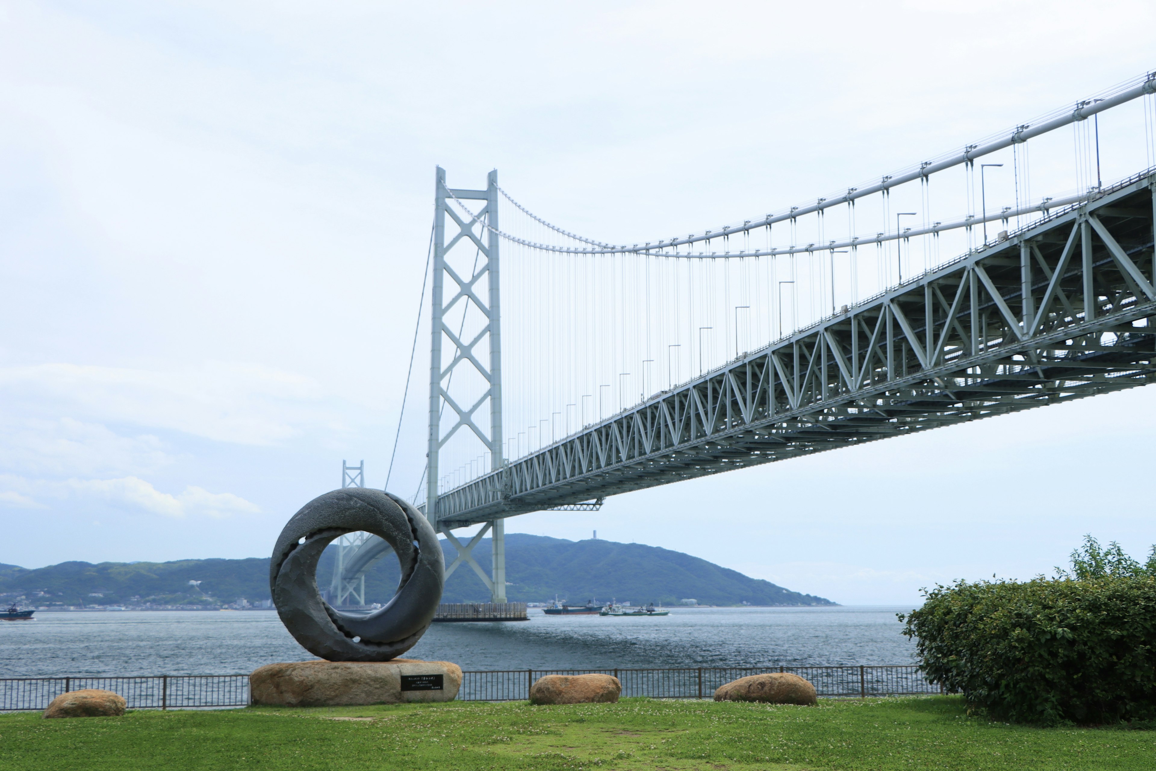 大きな円形の彫刻と橋が並ぶ海の風景