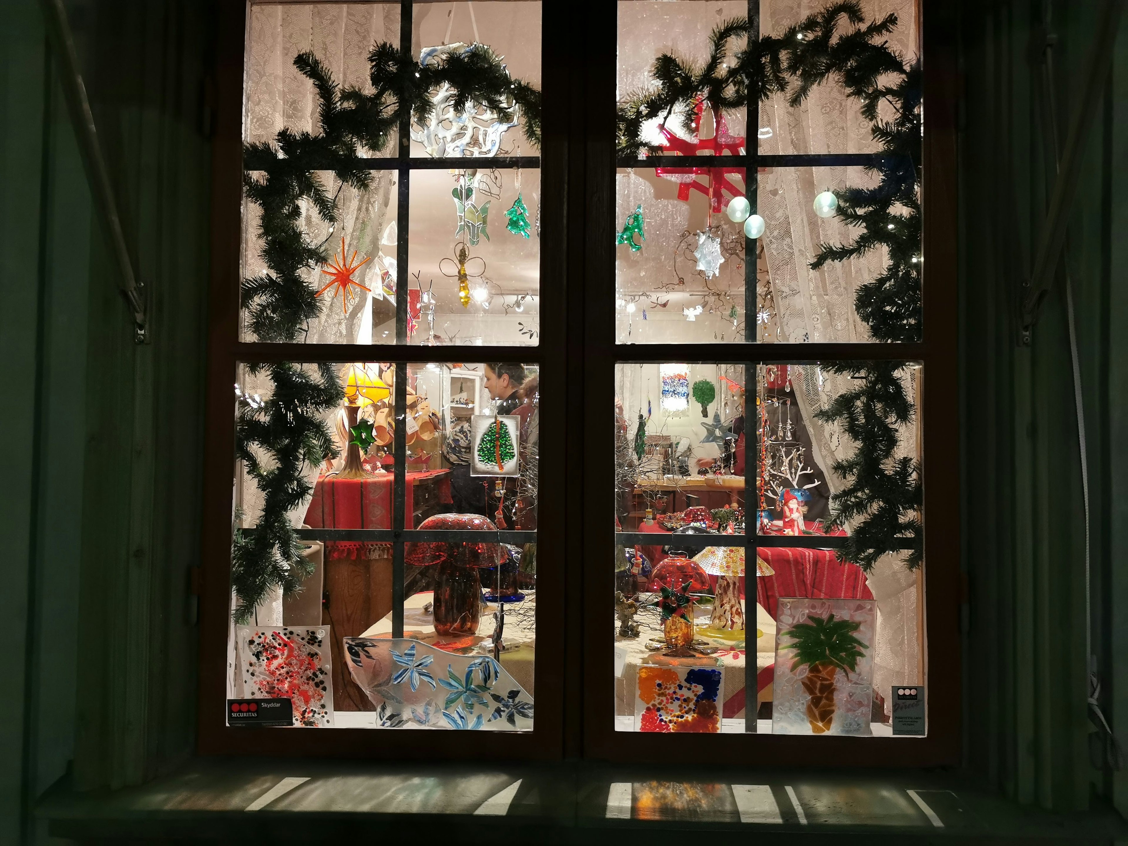 View of a window decorated for Christmas with colorful ornaments and warm lighting