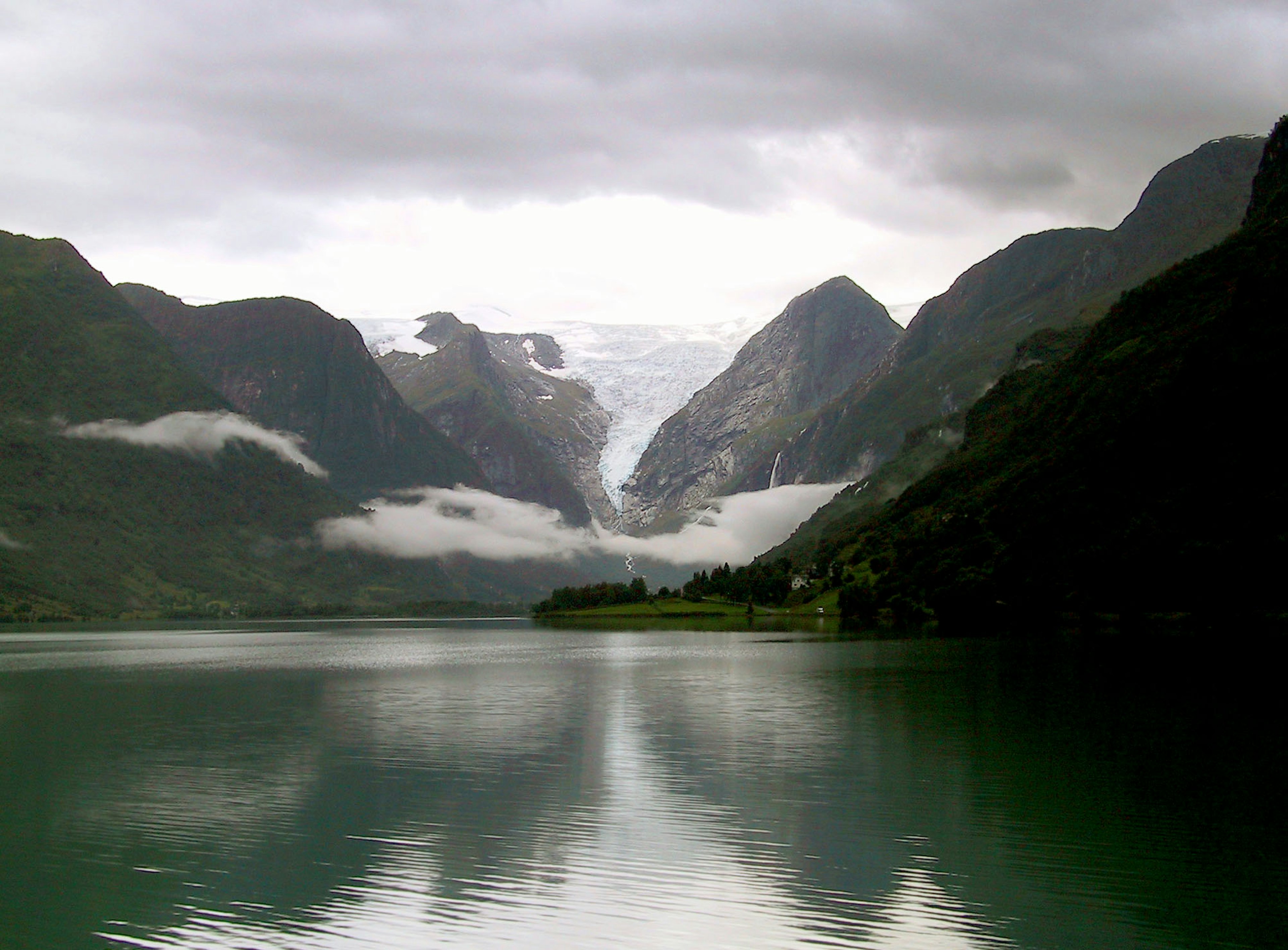 Serene lake with majestic mountains Cloudy sky with visible glacier